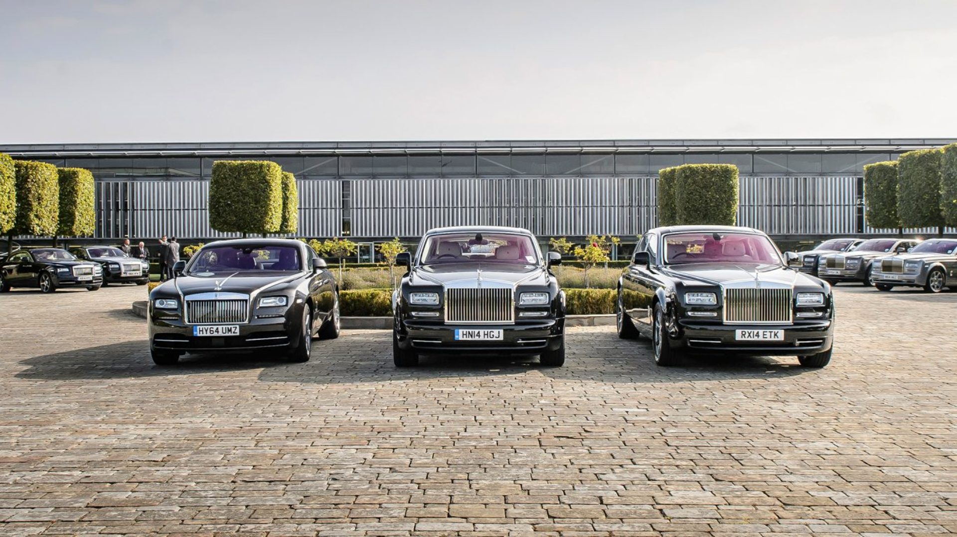Front exterior image of three Rolls-Royce motor cars in the courtyard at the factory in Goodwood.