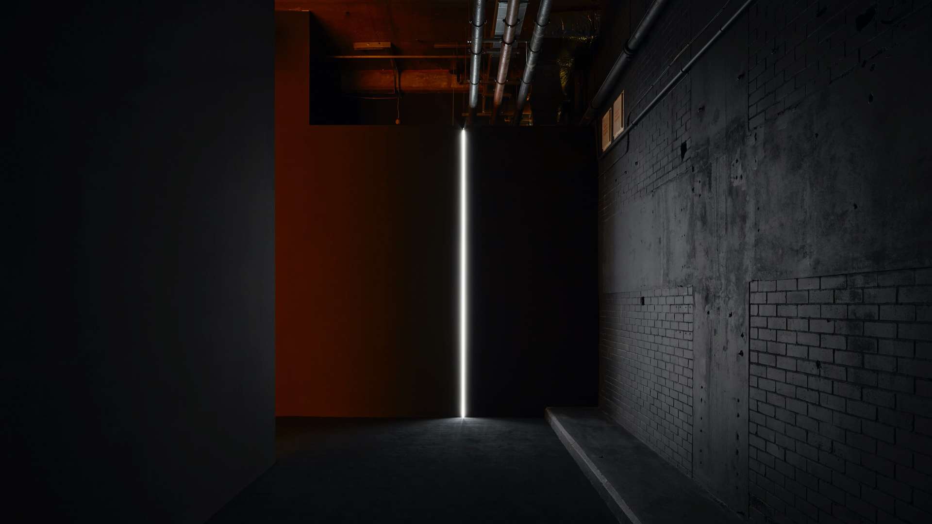 Artwork by Japanese visual artist Ryoji Ikeda's showing a thin strip of white light in a darkly lit interior space