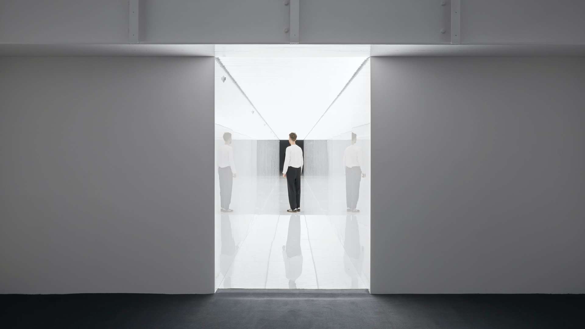 Artwork by Japanese visual artist Ryoji Ikeda's showing a person standing in a well-lit corridor