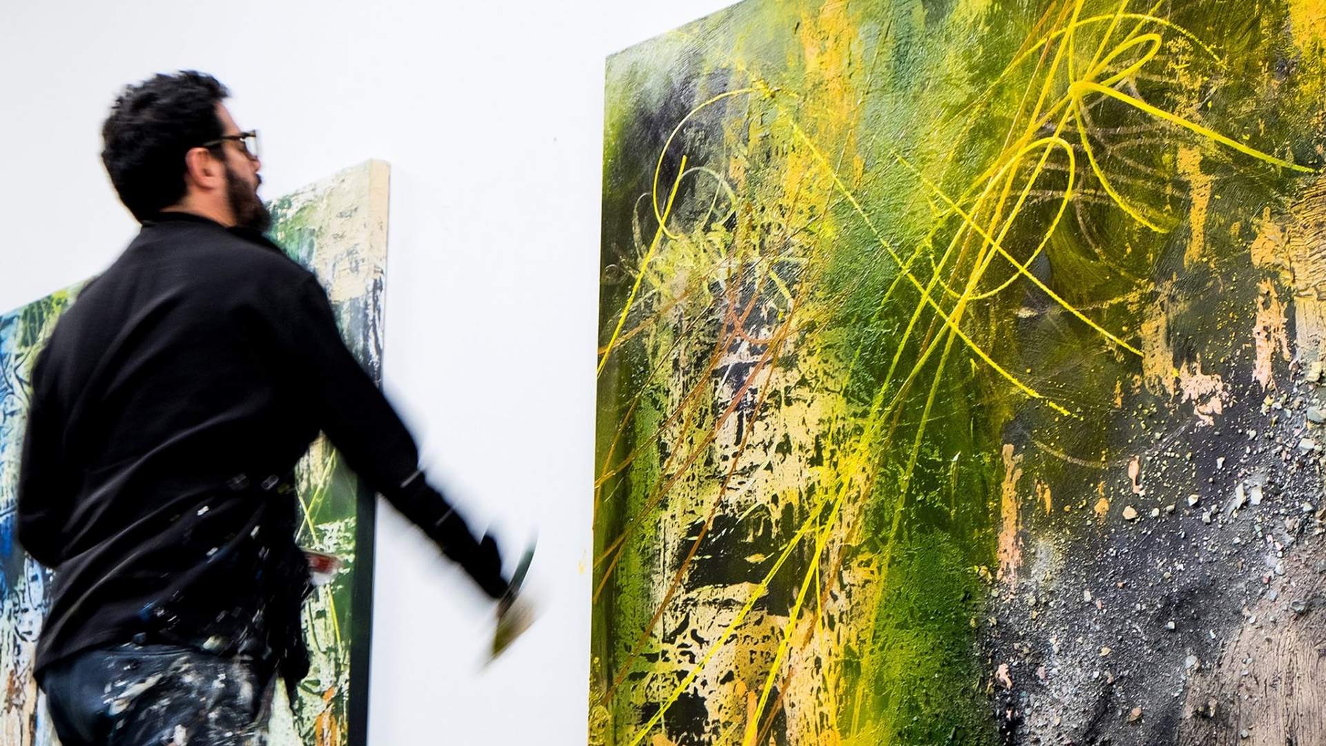 José Parlá standing in front of some of his art pieces. His work explores the connections between past and present by using colour and abstract calligraphy