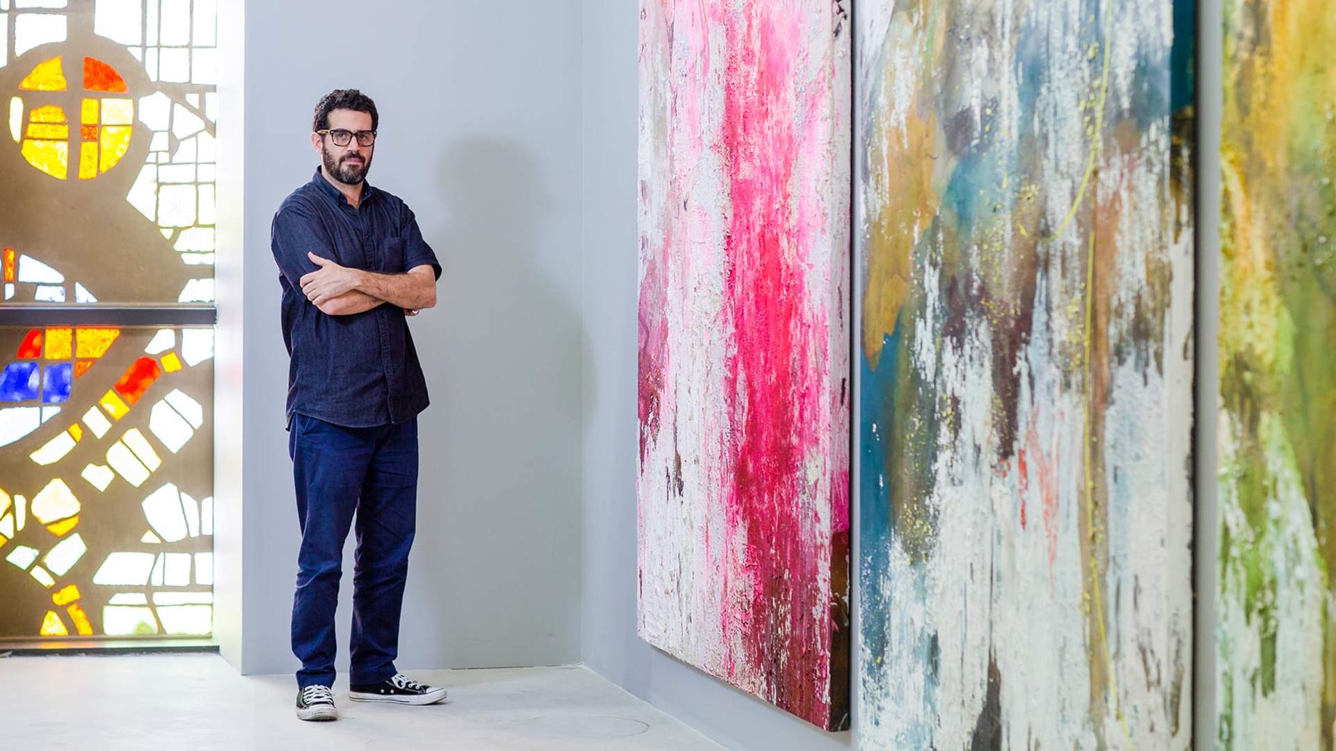 José Parlá standing in front of some of his art pieces. His work explores the connections between past and present by using colour and abstract calligraphy