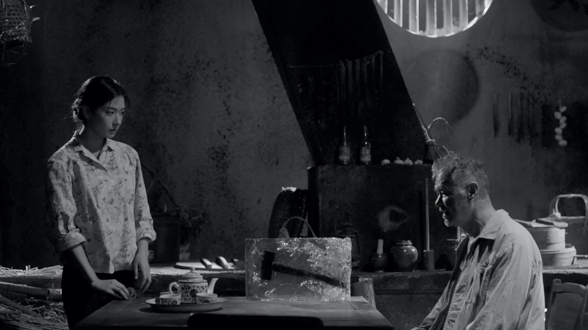 A still from 'Moving Mountains' - Depicts a kitchen scene showing a man and a woman talking, in black and white
