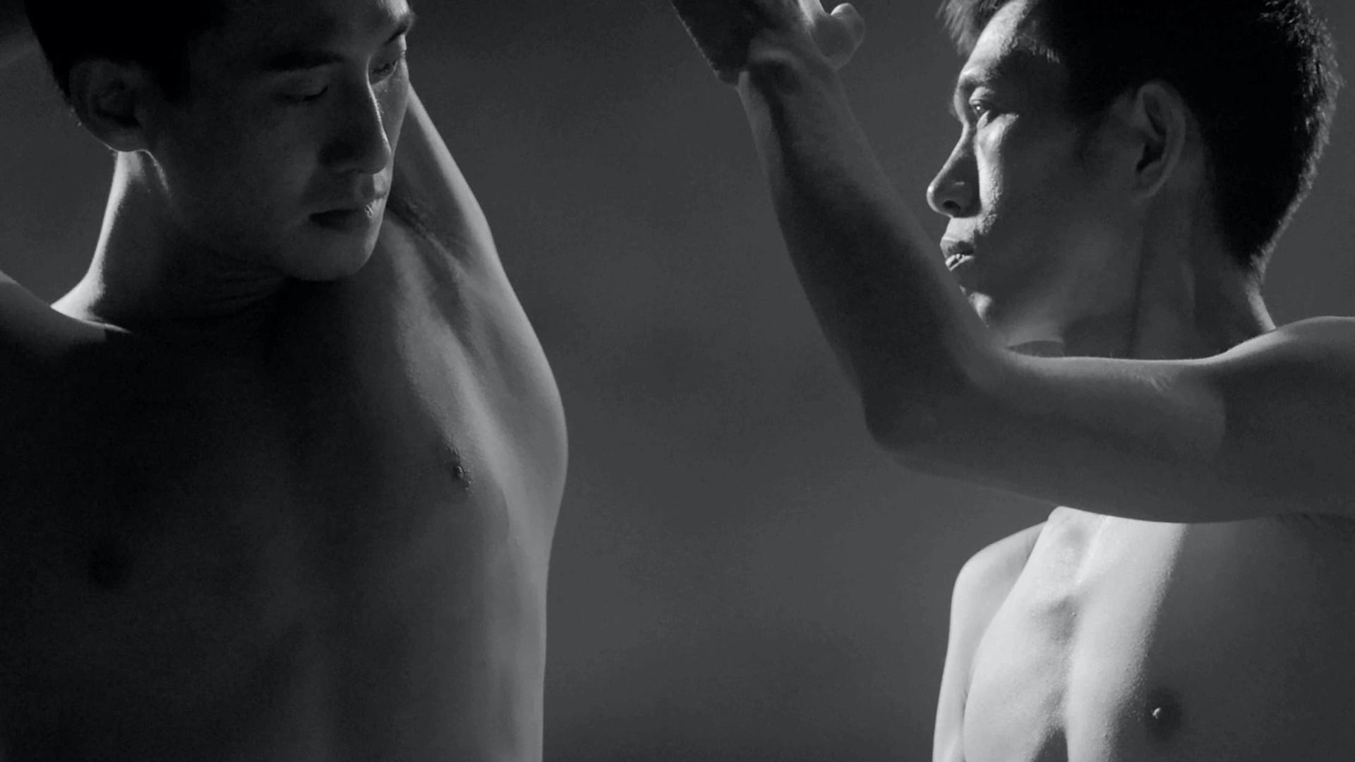A still from 'Moving Mountains' - Depicts two men looking at one another, shirtless, black and white