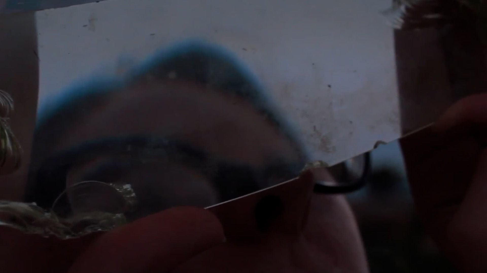 Still from 'Gosila' film - shows a reflection of a face in broken glass