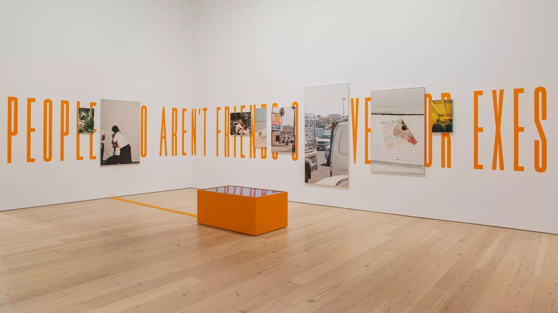 A shot of the installation of 'Intro to Threat Modelling' - shows a number of canvases hung on a white wall breaking up capitalised orange words