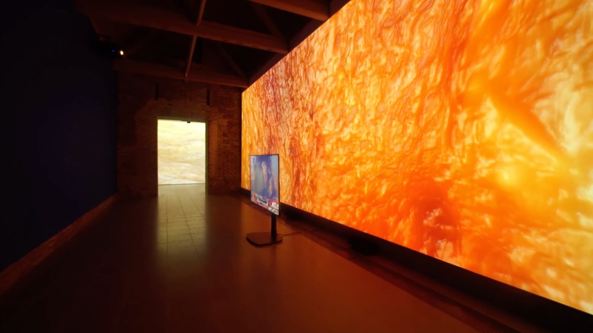 'Typhoon Coming on' still - Shows a long hallway with an orange and red video wall