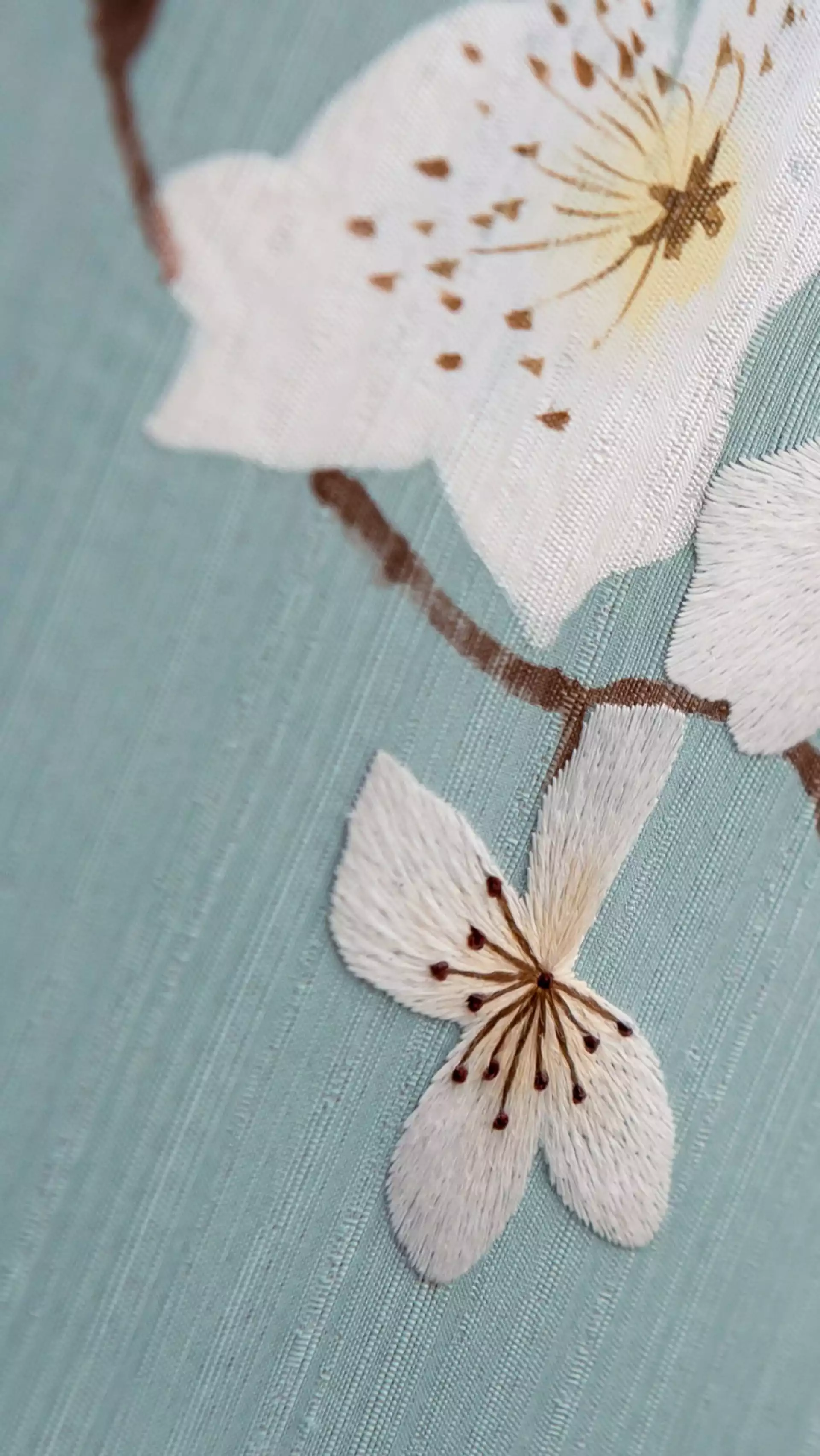 Discover the artistry of an icon enveloped in fine Chinese silk and embroidered with a hand-painted blossom motif.