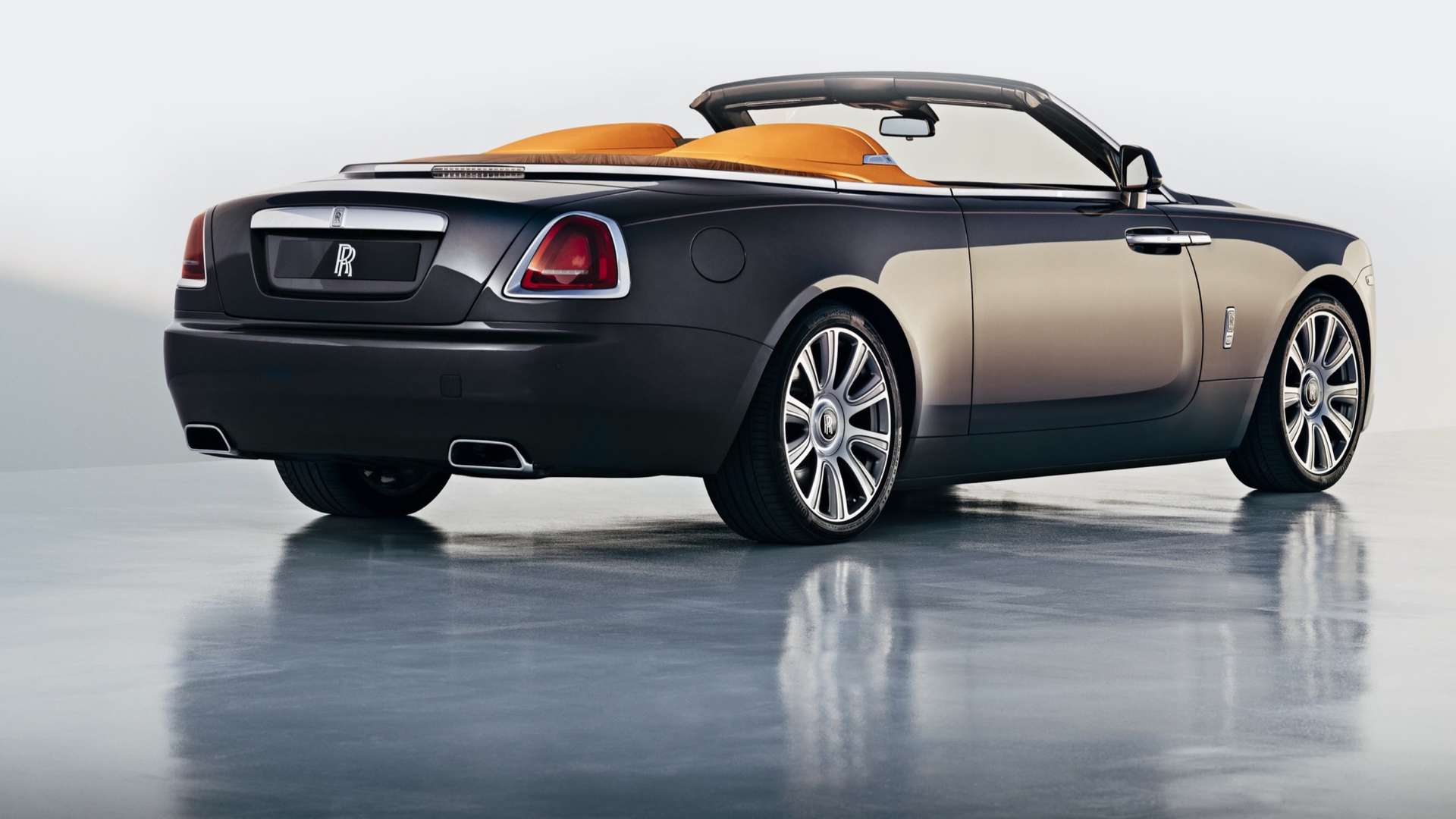 A rear view of a grey Rolls-Royce Dawn with its roof down.