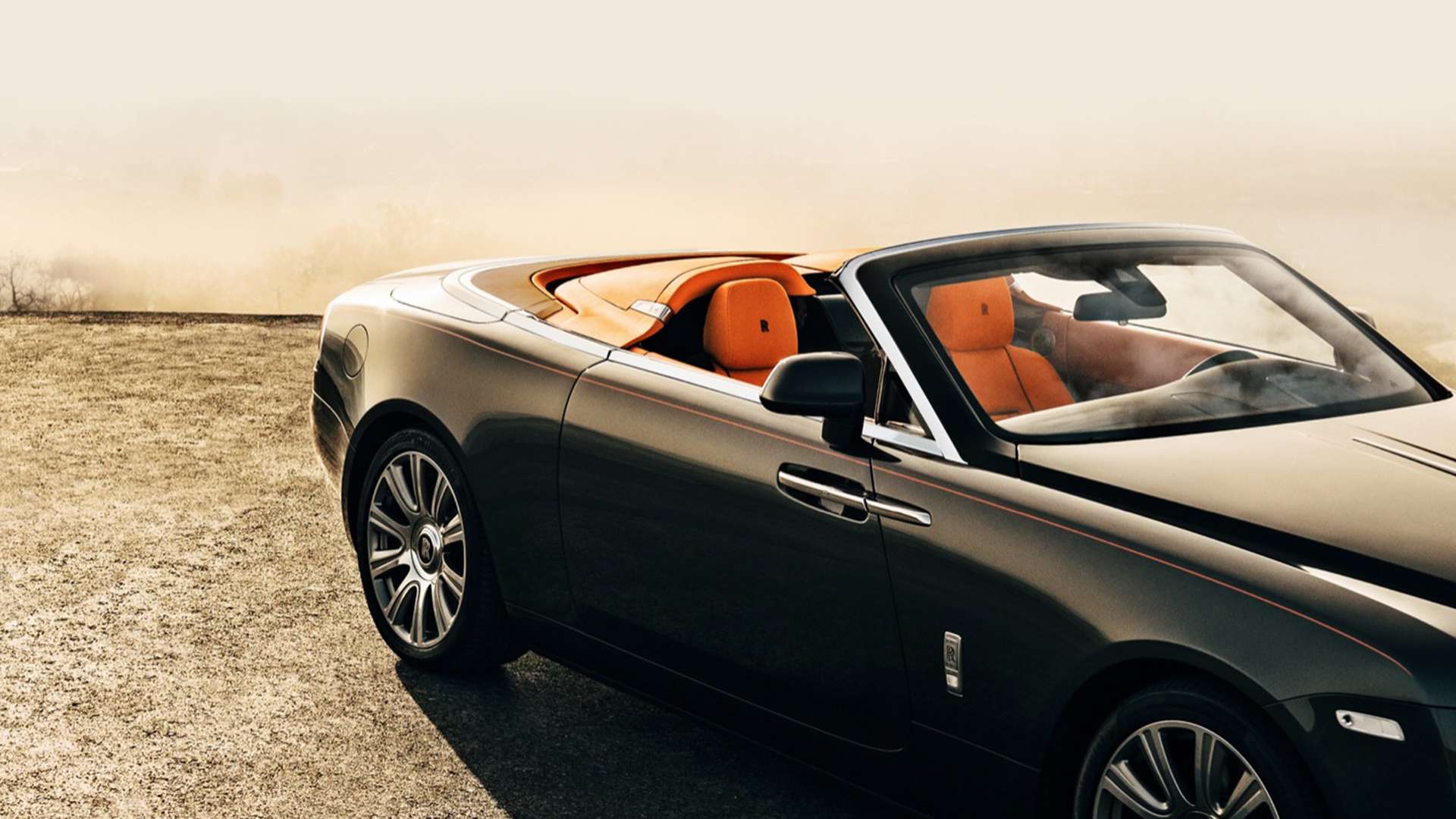 A grey Rolls-Royce Dawn with its roof down, showing its leather seating.