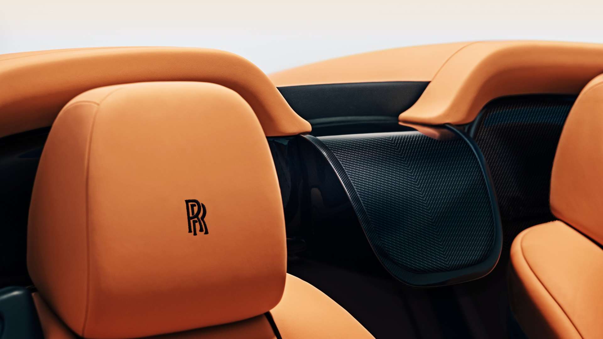A close up of an orange leather headrest on a convertible Rolls-Royce Dawn