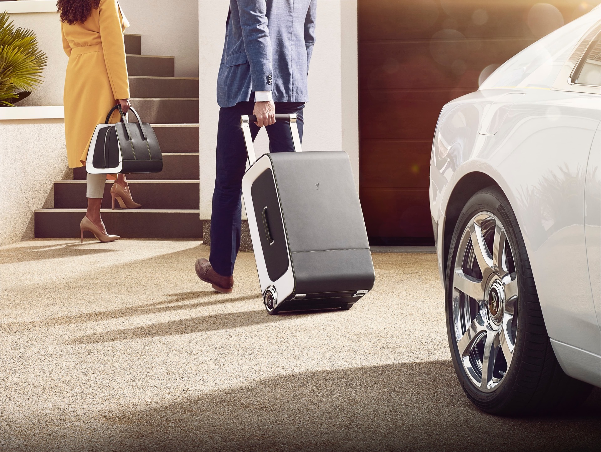 Wraith Luggage - 손에 드는 가죽 백을 든 여성과 가죽 가방을 끌고 있는 남성