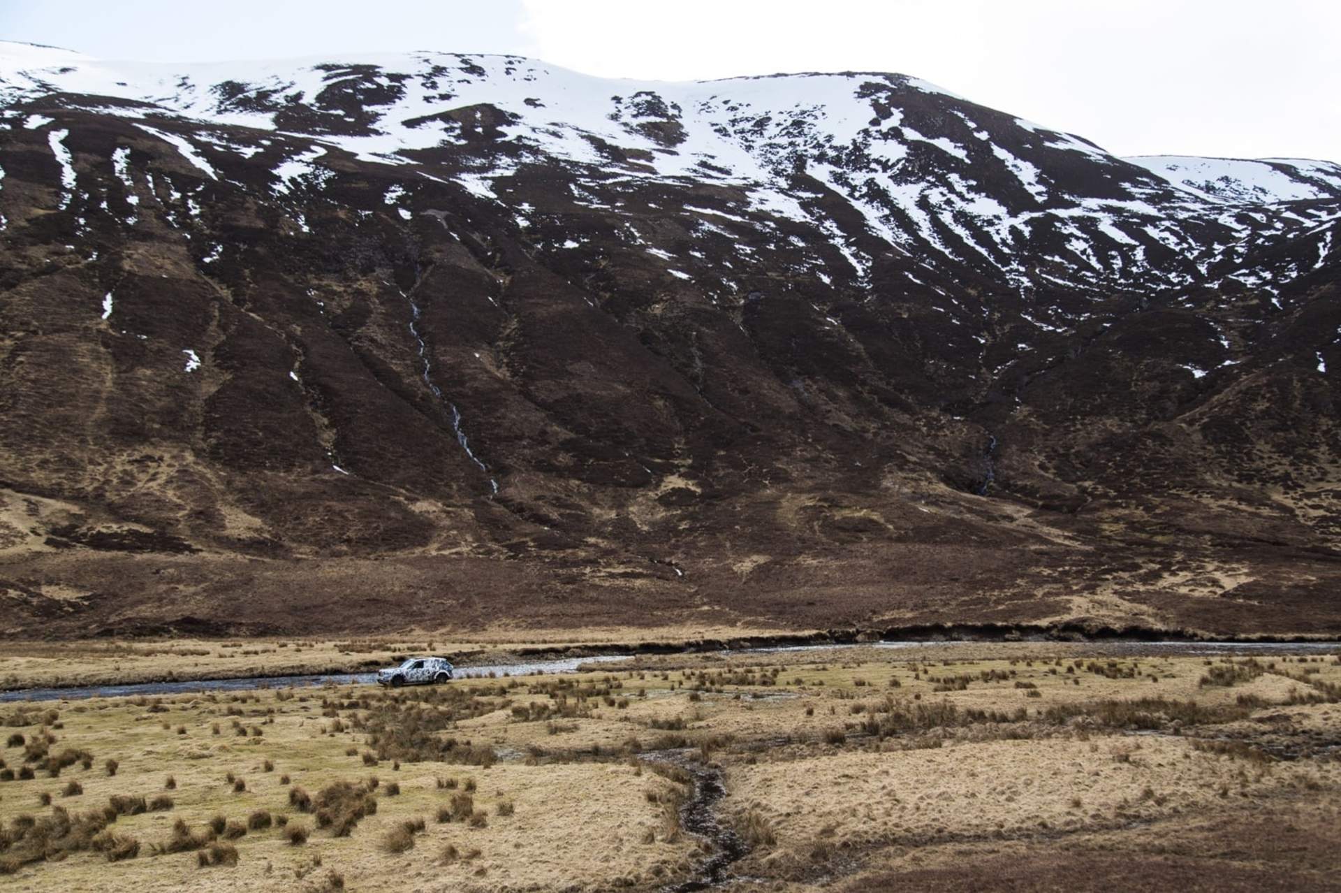 A Rolls-Royce Cullinan motor car drives through mountainous terrain