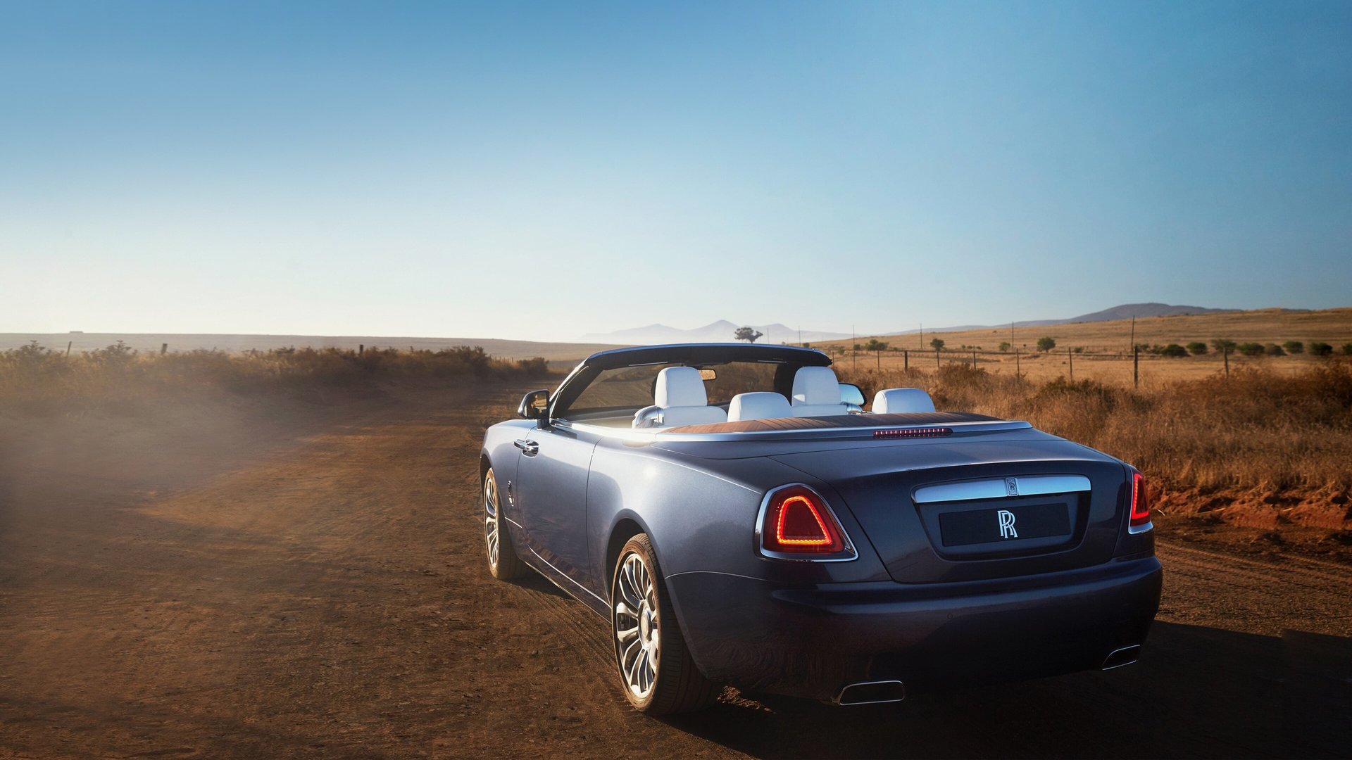 3/4 rear exterior view of the drophead coupé Rolls-Royce Dawn motor car in expansive dry, sunny landscape
