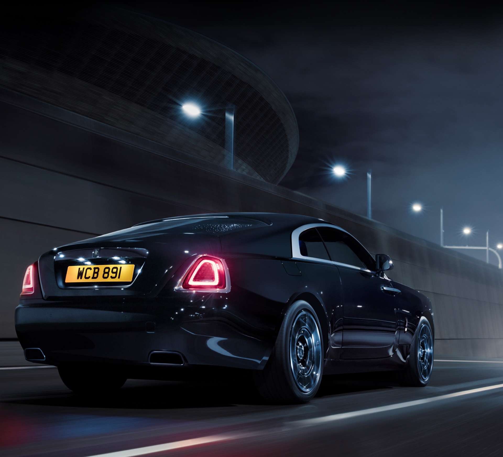 3/4 rear exterior view of the Rolls-Royce Black Badge Wraith motor car driving at night