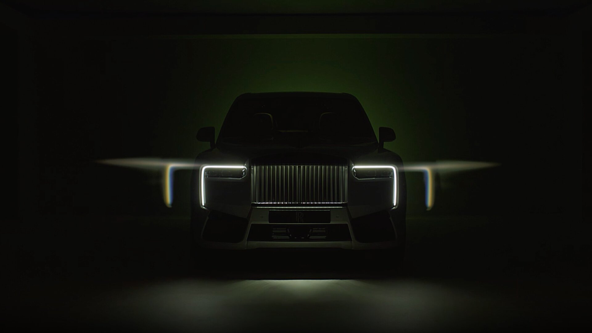 Image showcasing the incredible lighting of the Black Badge Cullinan Series II . A front shot of the headlights and grille, sitting in a dark room. 