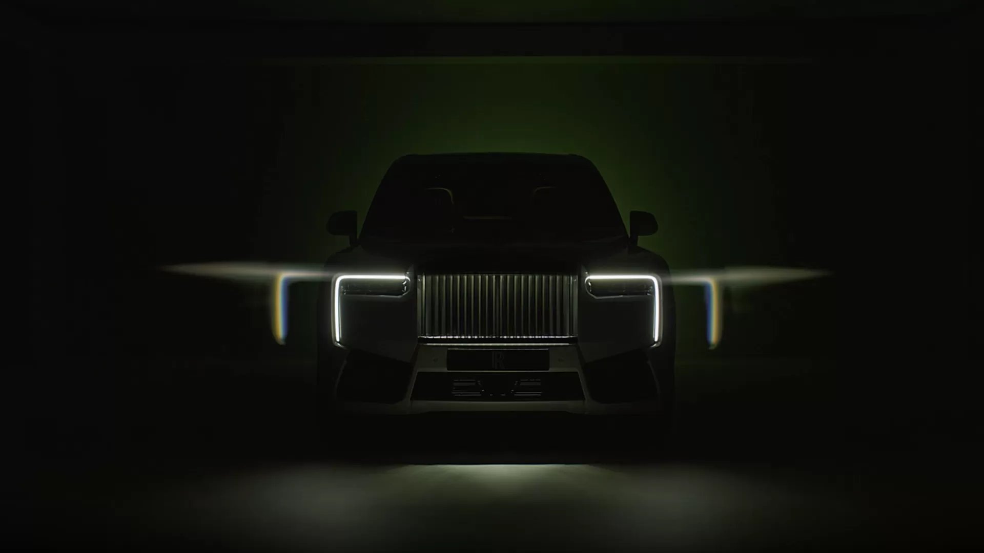 Image showcasing the incredible lighting of the Black Badge Cullinan Series II . A front shot of the headlights and grille, sitting in a dark room. 