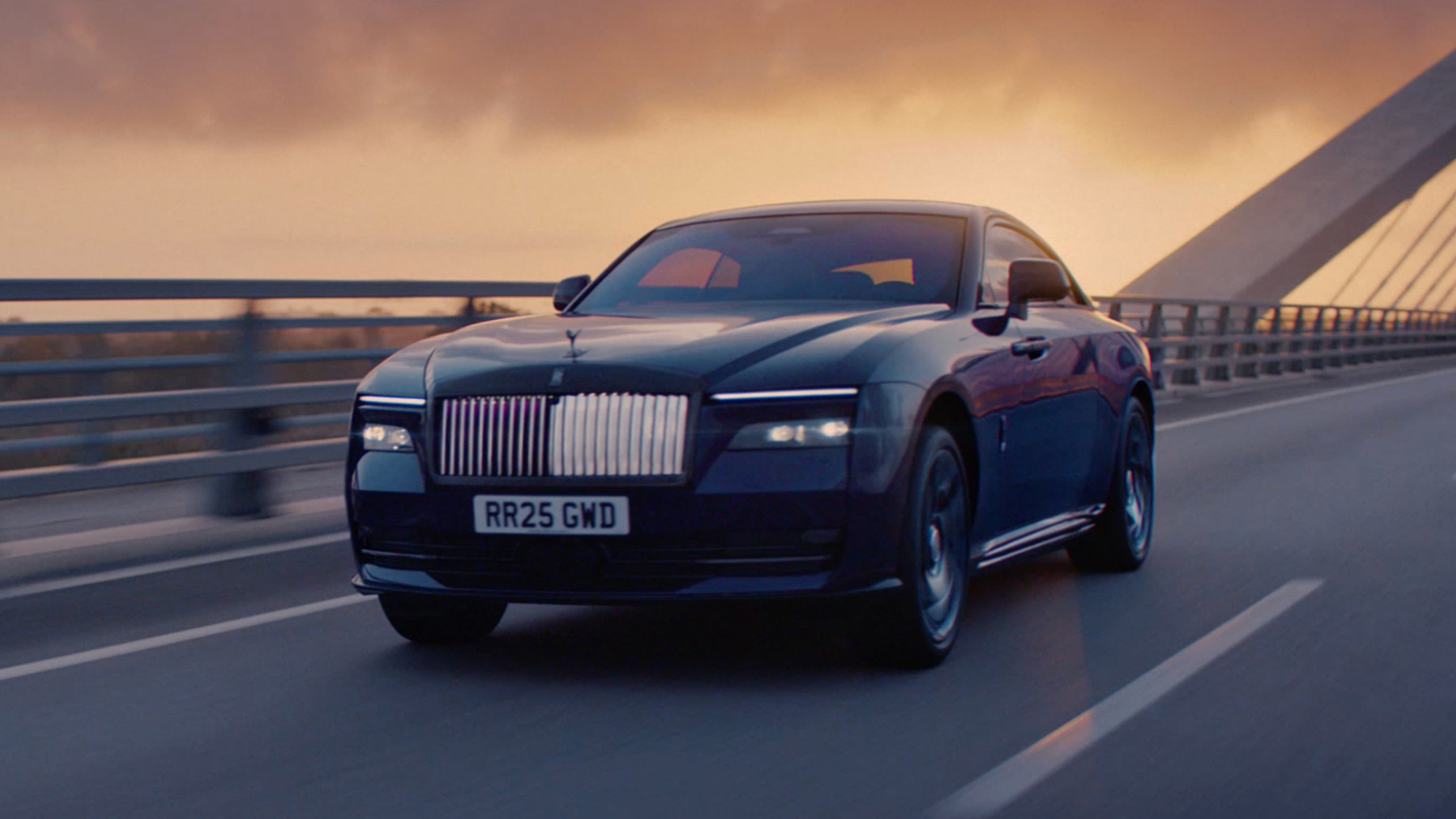 Action shot of a stone colour'd Black Badge Spectre driving on a bridge, just in time to catch the sunrise. 