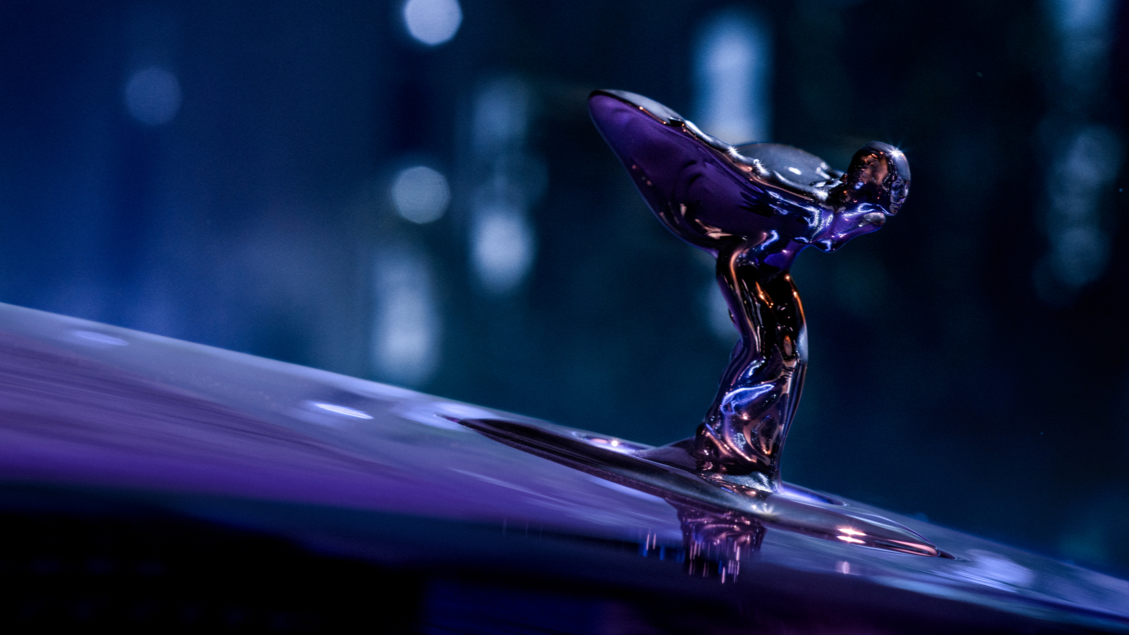 Close up shot of the Spirit of Ecstasy, radiating a purple hue from the purple Black Badge Spectre.