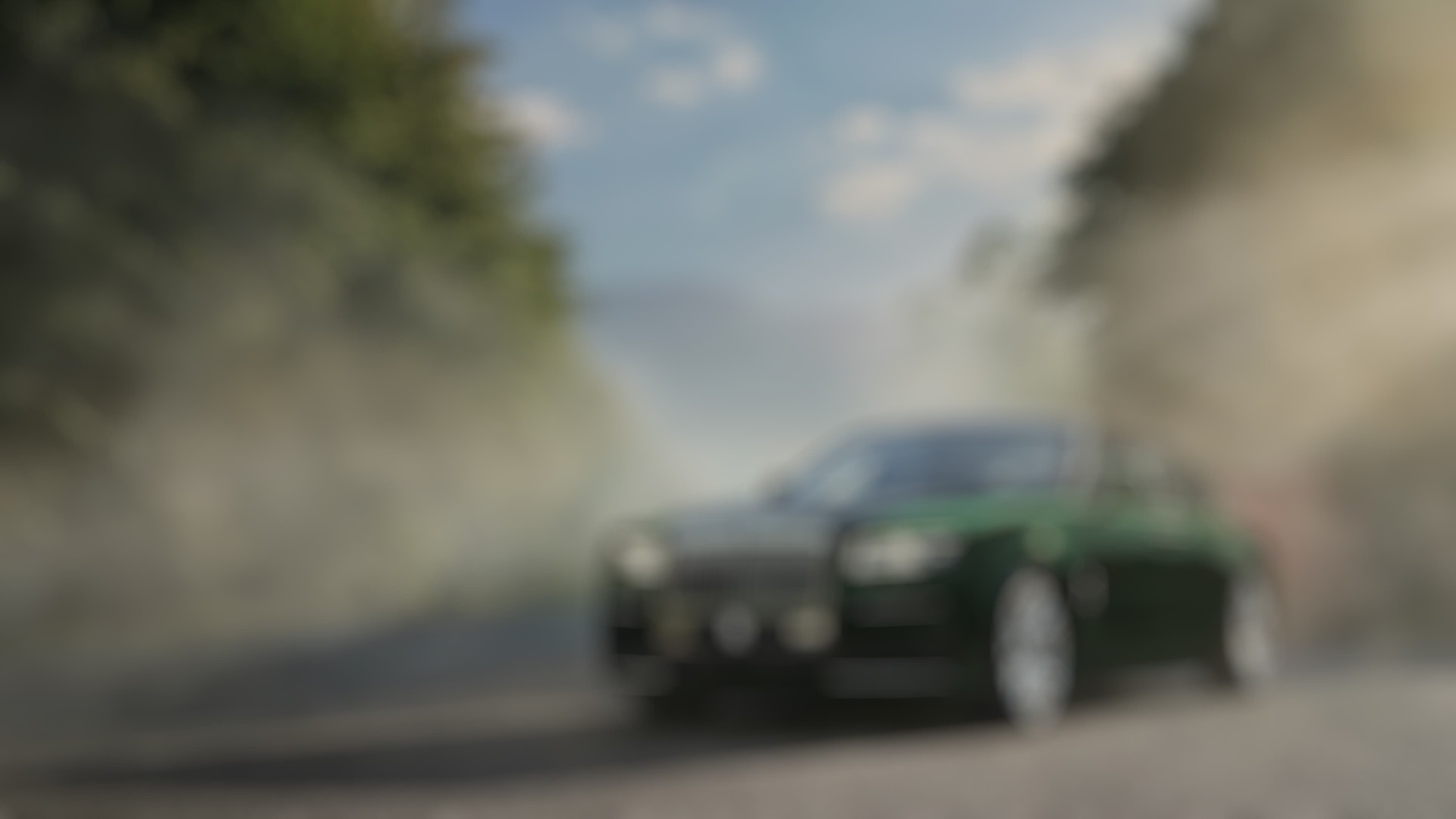 3/4 front exterior of stationary Rolls-Royce Ghost Extended motor car on road with trees and mountains behind