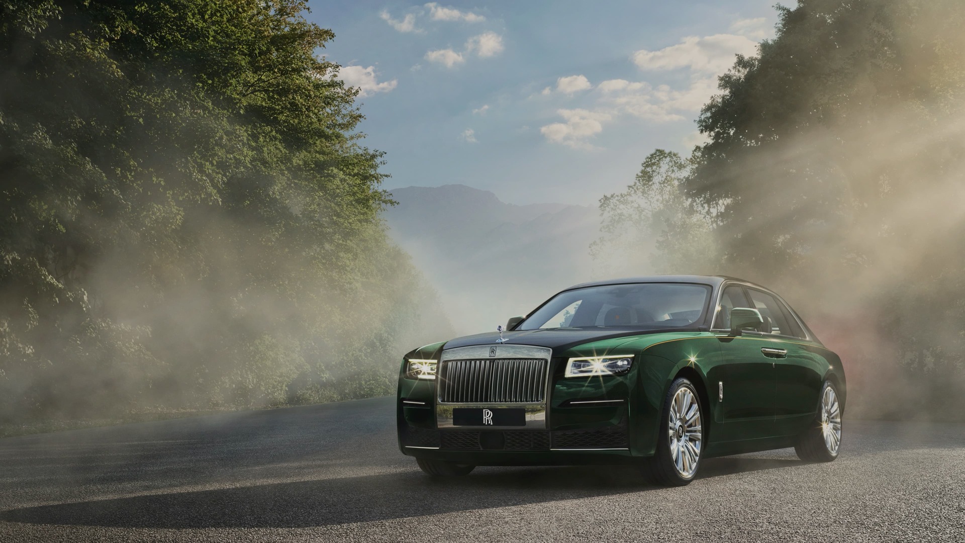 3/4 front exterior of stationary Rolls-Royce Ghost Extended motor car on road with trees and mountains behind