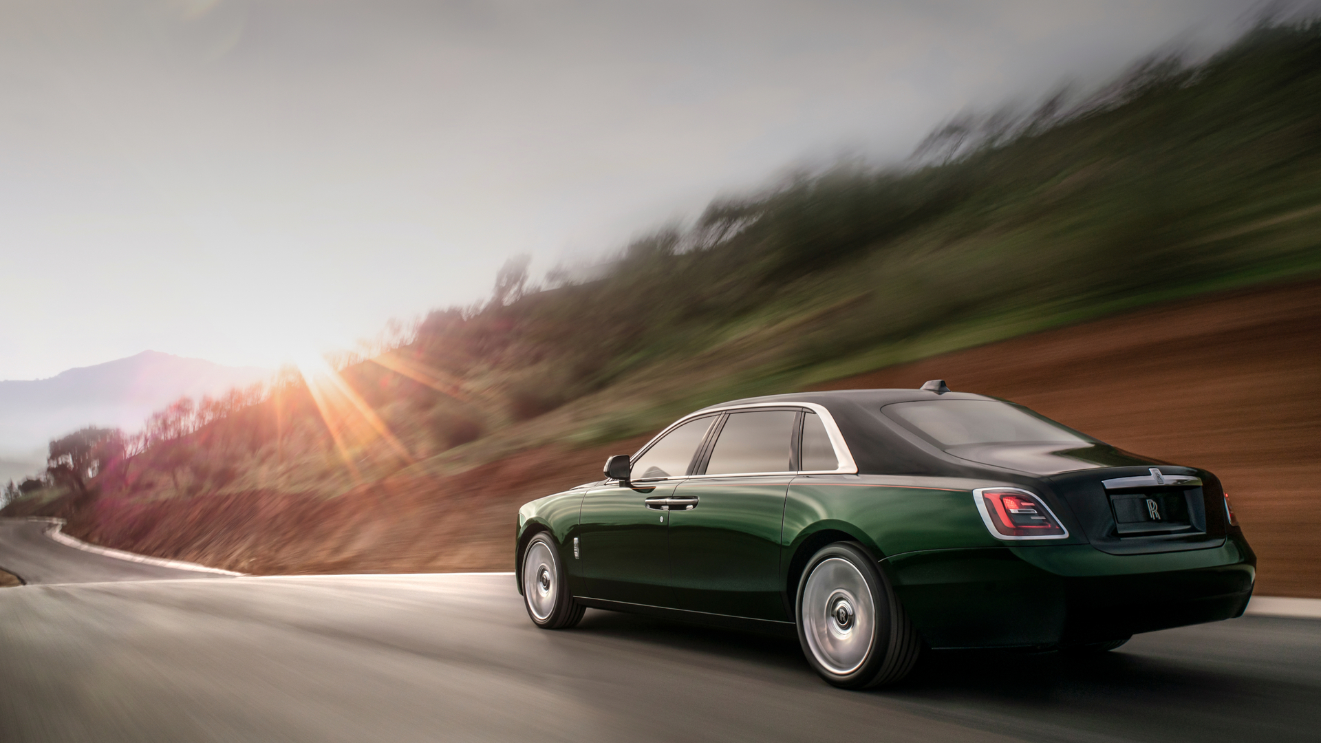 Side profile of the a green Ghost Extended driving towards the sunset on the road