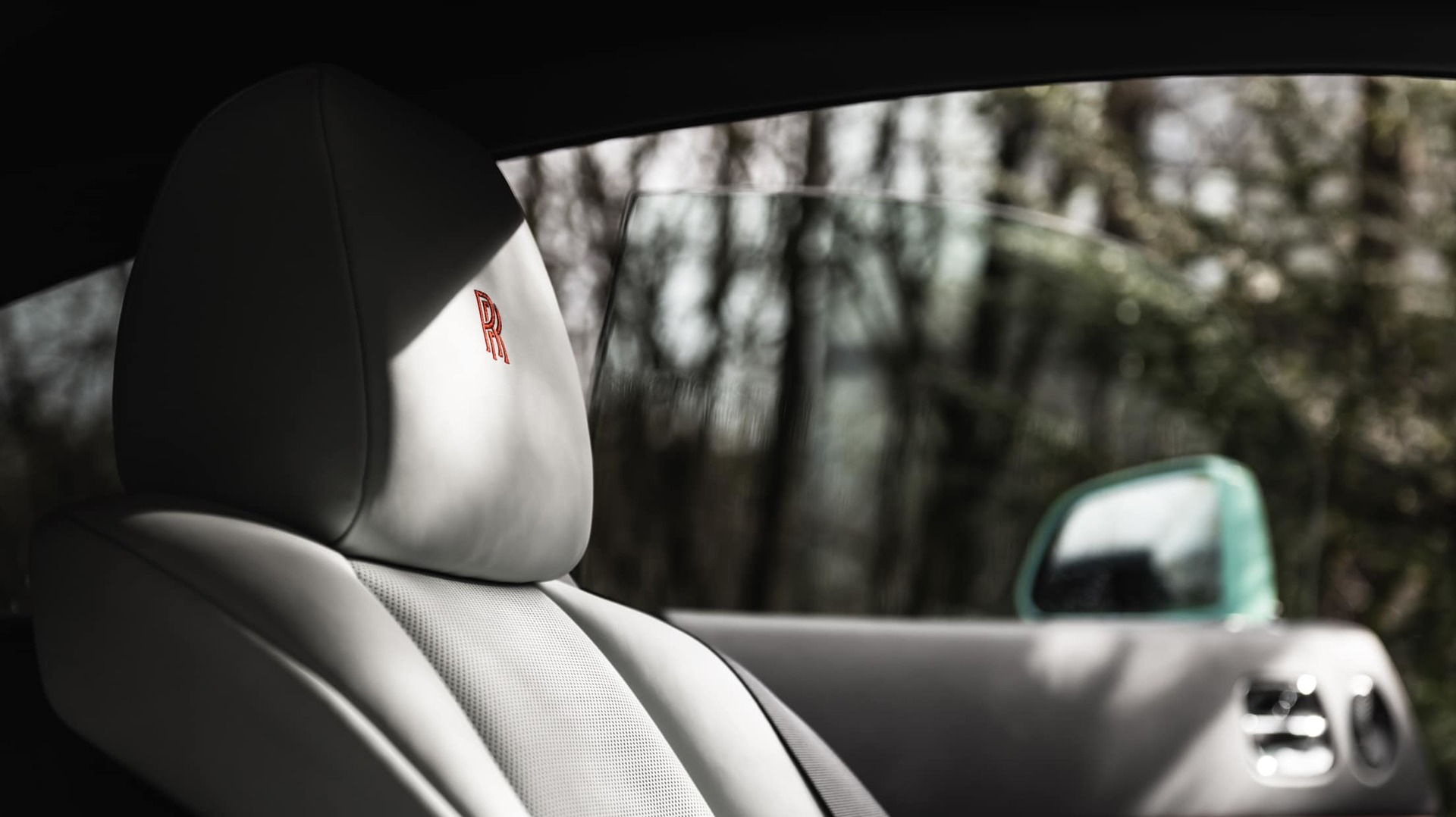 Bespoke headrest detail with Rolls-Royce monogram in Koi Red in Black Badge Wraith Inception motor car