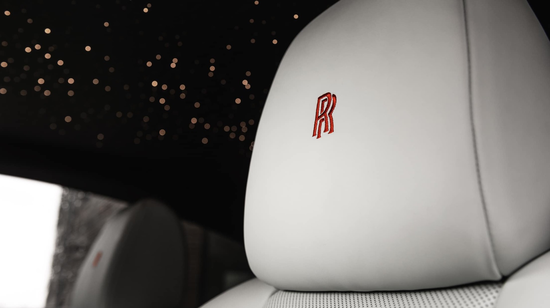 Interior of Rolls-Royce motor car with starlight headliner and bespoke, personalised headrest with signature monogram