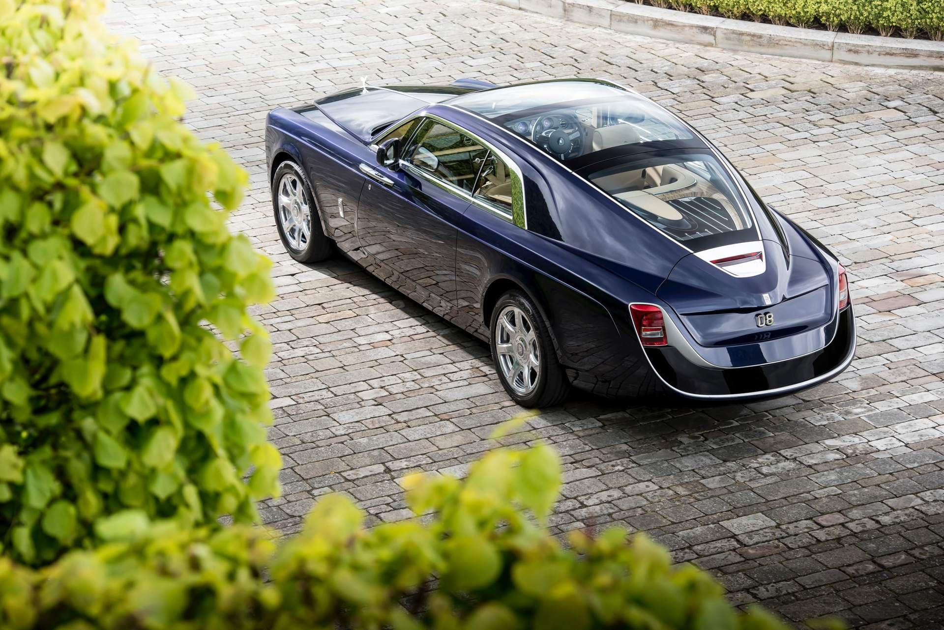 Exterior view of the unique Rolls-Royce Sweptail motor car with greenery in the foreground