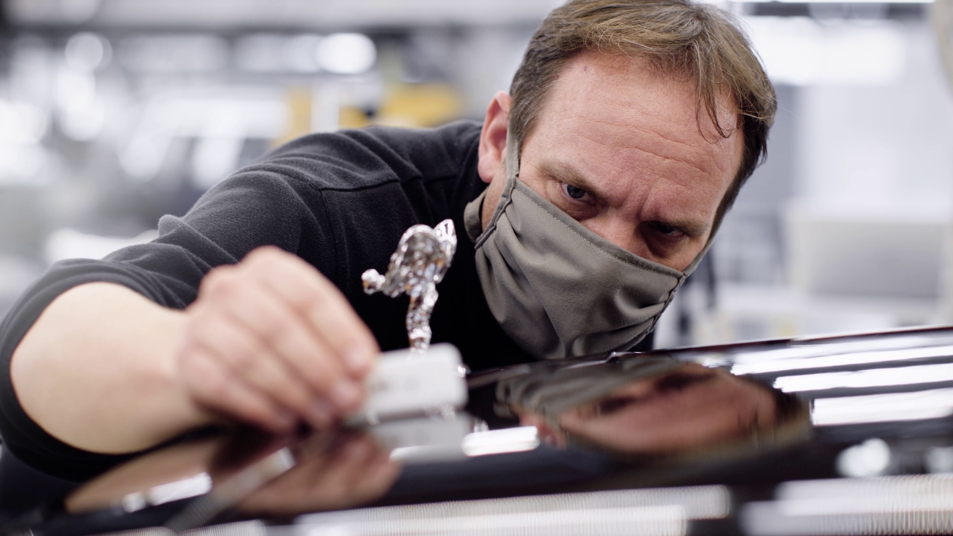 A Rolls-Royce engineer fitting a Spirit of Ecstasy onto a Rolls-Royce motor car
