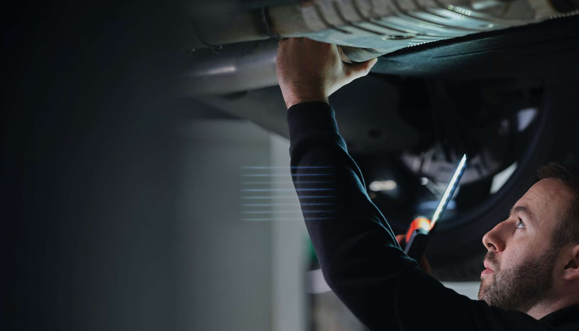 A technicial working on the bottom of a Rolls-Royce car