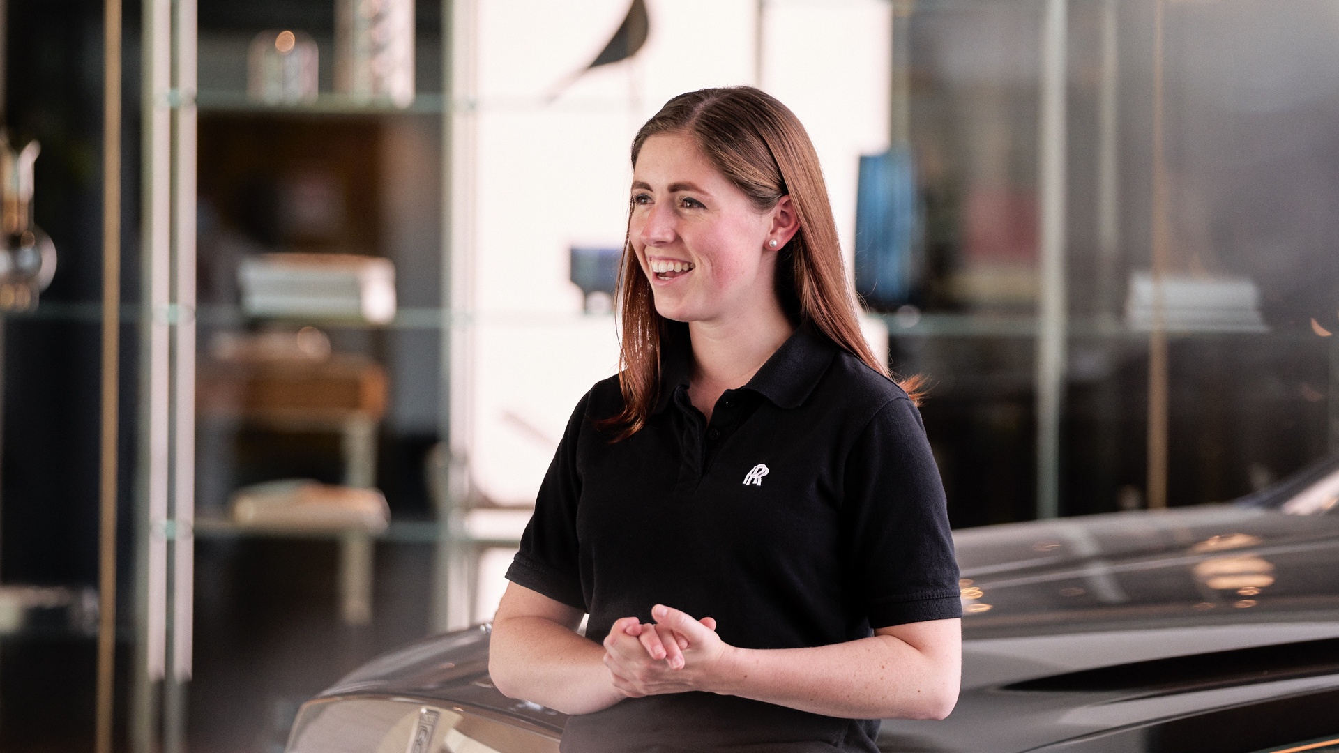 A young woman wearing a polo shirt with the Rolls-Royce monogram on it