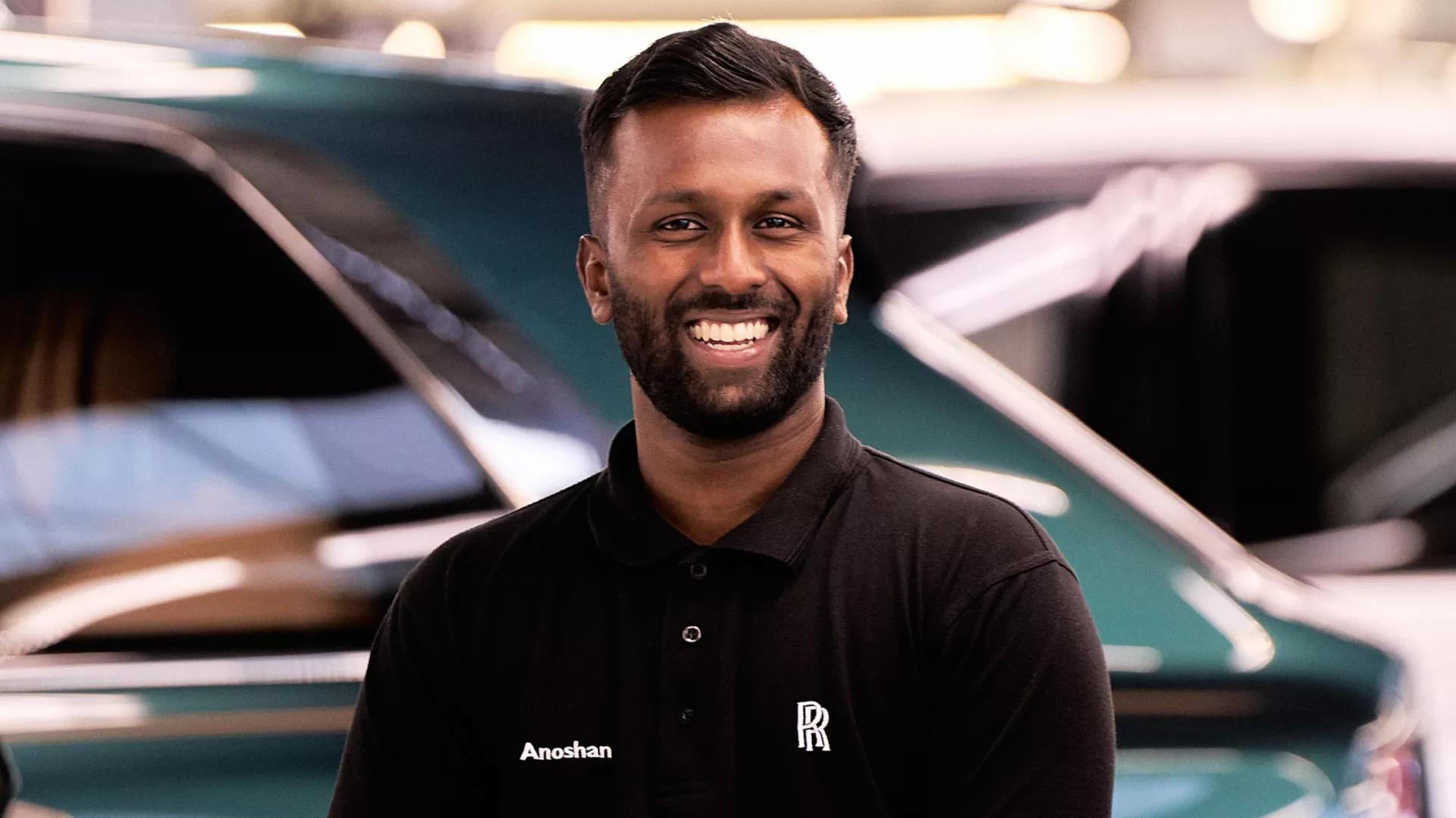  A young Rolls-Royce graduate wearing a polo shirt with the name Anoshan and the Rolls-Royce monogram on it