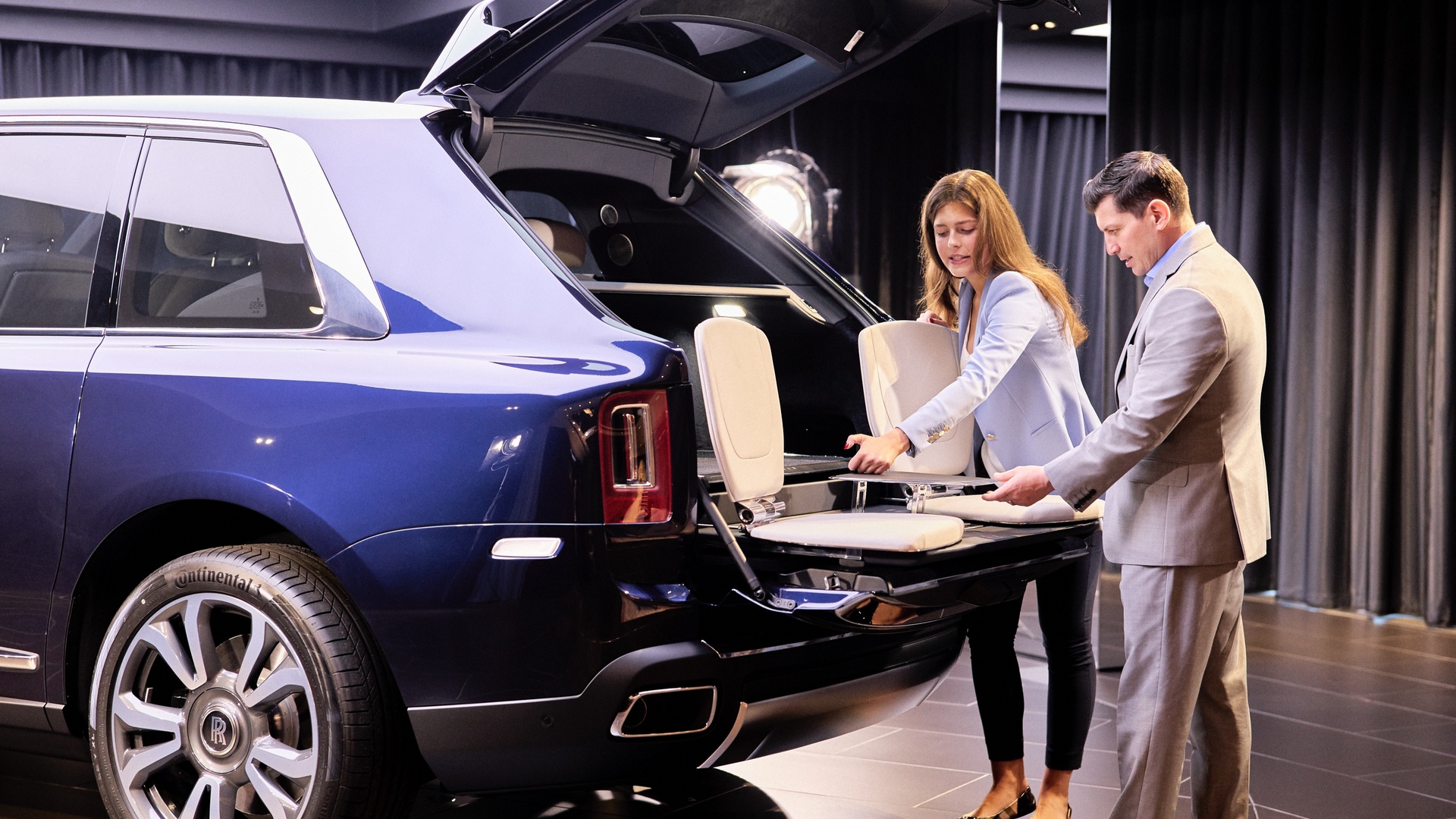 A woman and a man reviewing the Cullinan Viewing Suite accessory on a Rolls-Royce Cullinan car
