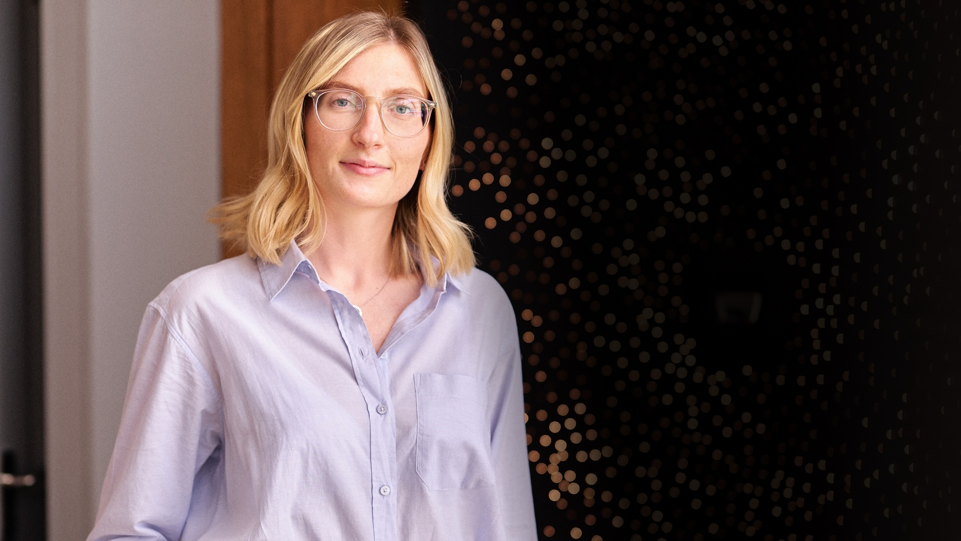 A young woman with blonde hair is wearing a purple shirt
