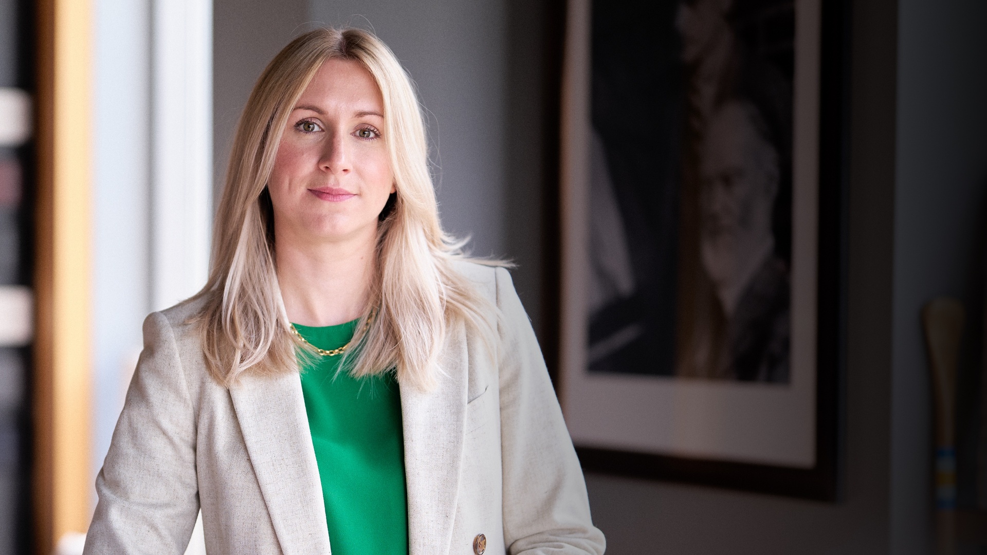 A close up of a woman with blonde hair wearing a jacket suit