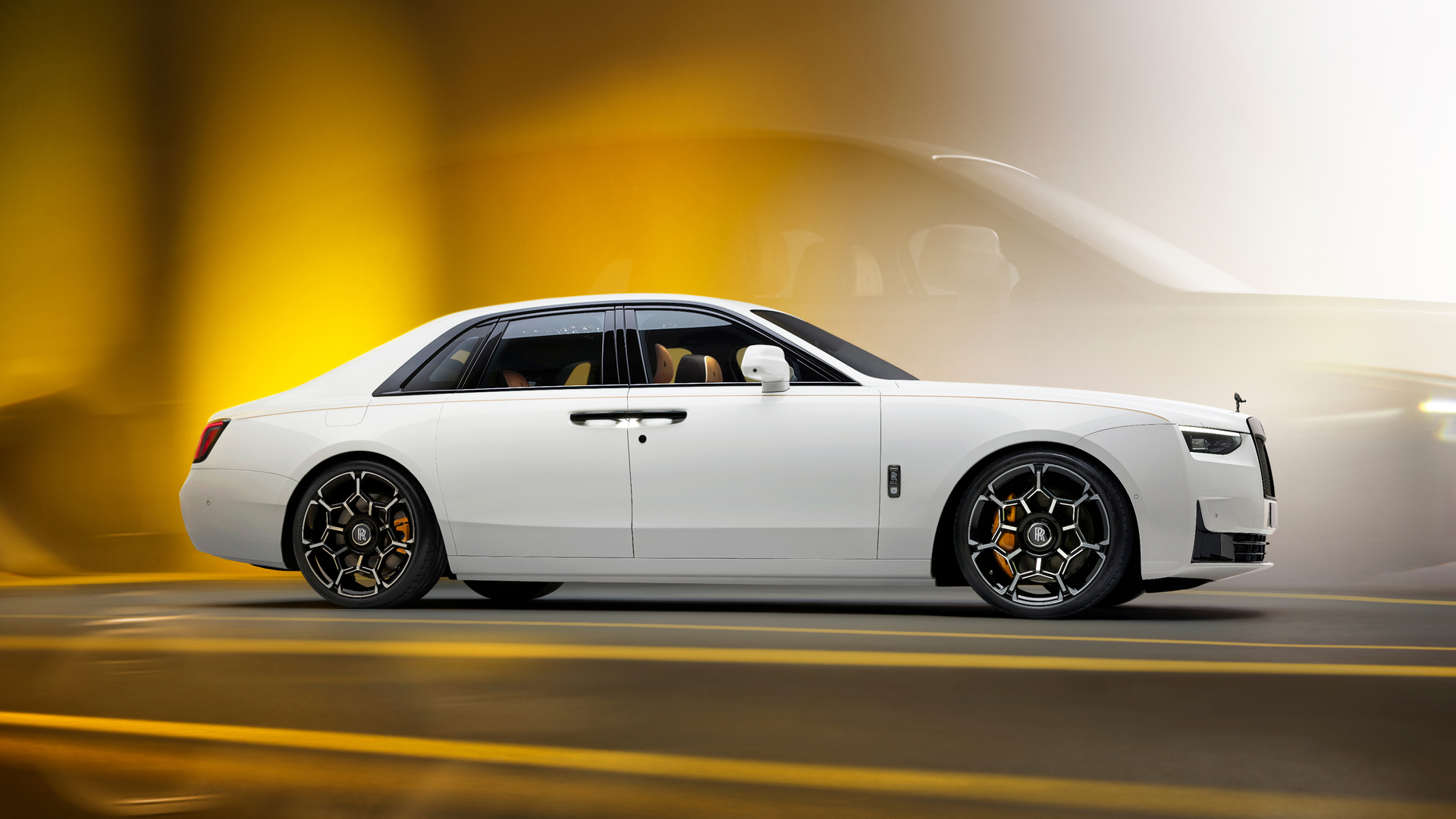 Side profile of a white Black Badge Ghost SII with Yellow Caliber breaks. Sitting on a yellow and black backdrop.