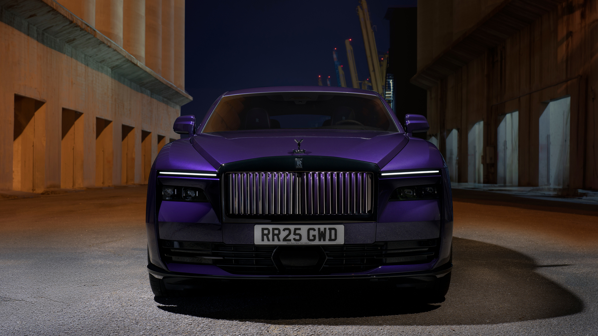 Front car angled shot, showcasing the purple Black Badge Spectre and the detailed silver grille parked outside a building on a late evening.