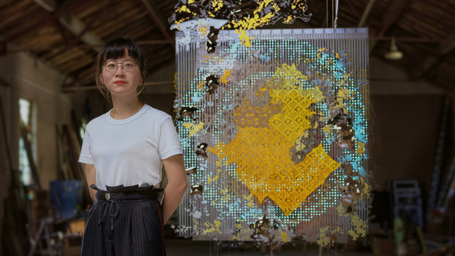 A photo of Bi Rongrong with her artwork in the backgorund