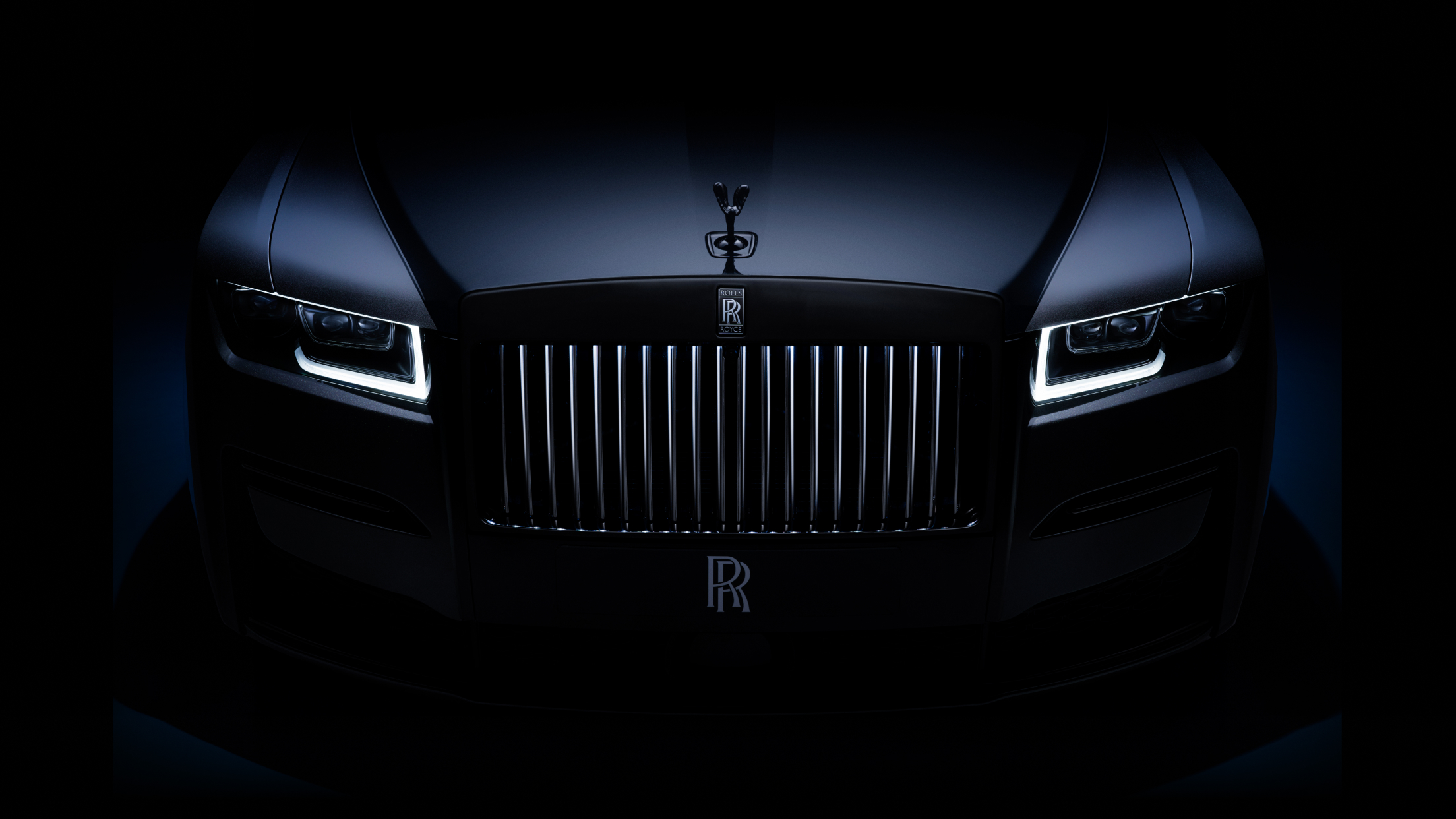 Front view of a Rolls-Royce Ghost in the dark with the lights on