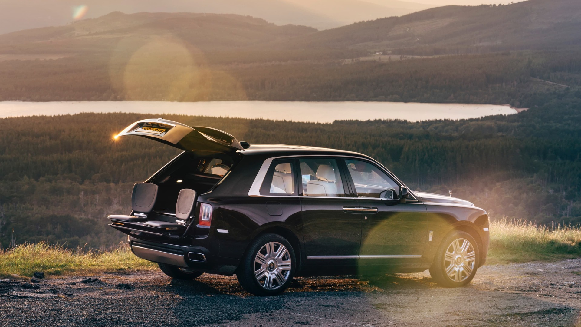 Exterior view of stationary Rolls-Royce Cullinan motor car with rear door open revealing the bespoke Cullinan Viewing Suite