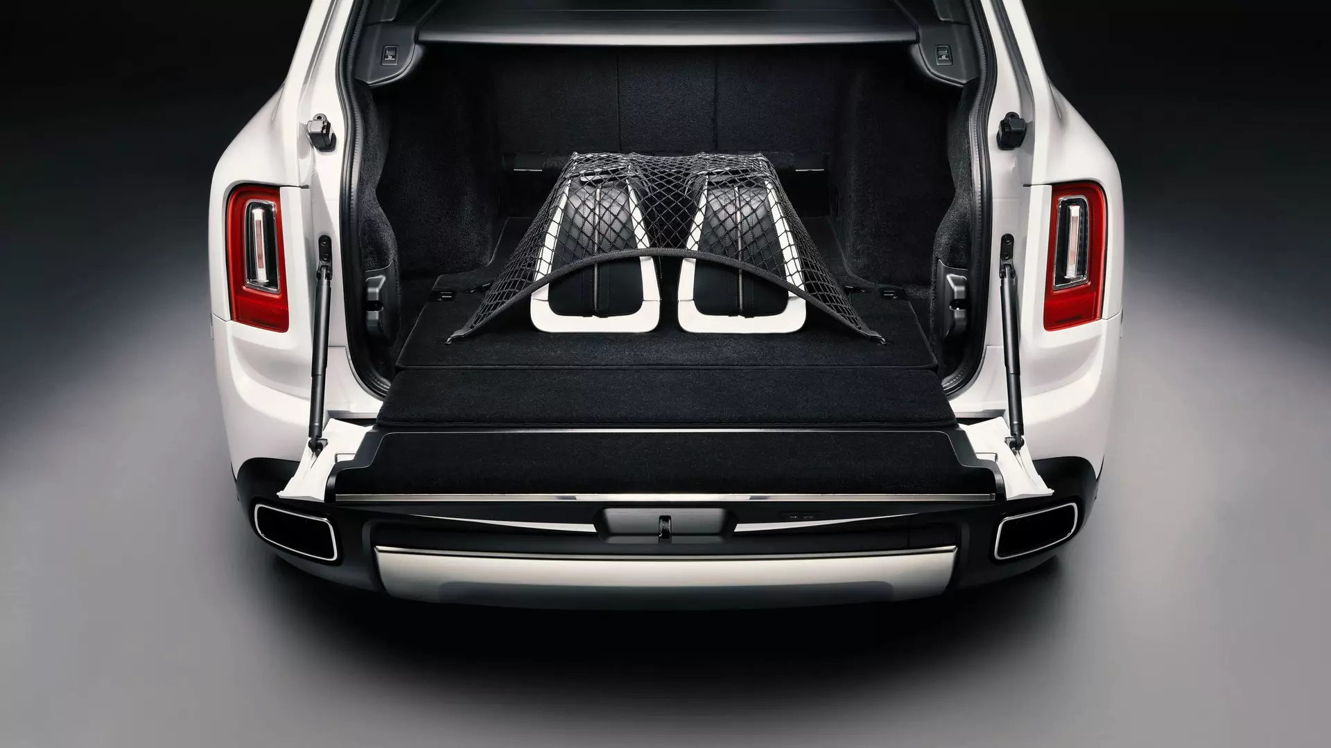 Rolls-Royce Cullinan motor car with rear door open revealing durable luggage net and luggage