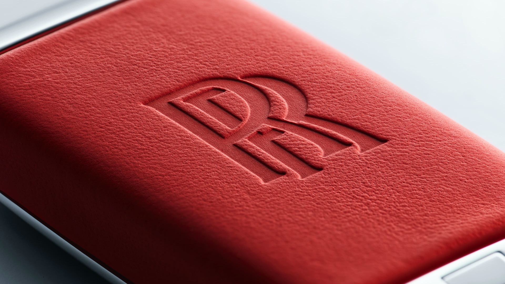 Close front view of a personalised ardent red key back with Rolls-Royce motor car logo.