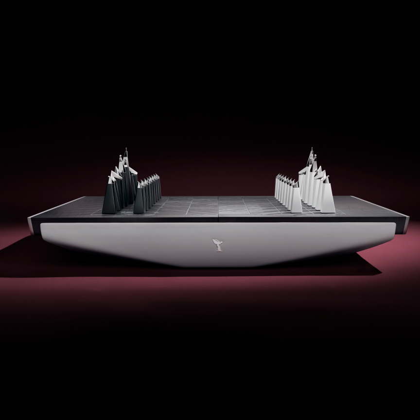 <p>Every detail of the Rolls-Royce Chess Set exudes elegance. The embedded chess pieces are ceremoniously unveiled, evoking the sense of occasion synonymous with the arrival of a Rolls-Royce motor car. Generous spacing around the chess board enhances the game’s theatrical allure, while the use of the finest materials, hand-fitted veneer, and polished details echo the superior craftsmanship found in Rolls-Royce interiors. </p>
<p>The playing board is available in a choice of four veneer combinations, each arranged to create a diamond pattern when viewed from above. Around the playing surface, a longitudinal grain is used, while within the playing field, the veneer is angled at 45 degrees to create a subtle contrast. High-gloss finishes include Blackwood with Ceramic White, and Macassar Ebony with Royal Walnut; Open Pore veneer treatments in Smoked Eucalyptus with Paldao and Obsidian Ayous with Blackwood are also available. The exterior and piece holder can also be personalised using one of thirteen Rolls-Royce leather colours.</p>