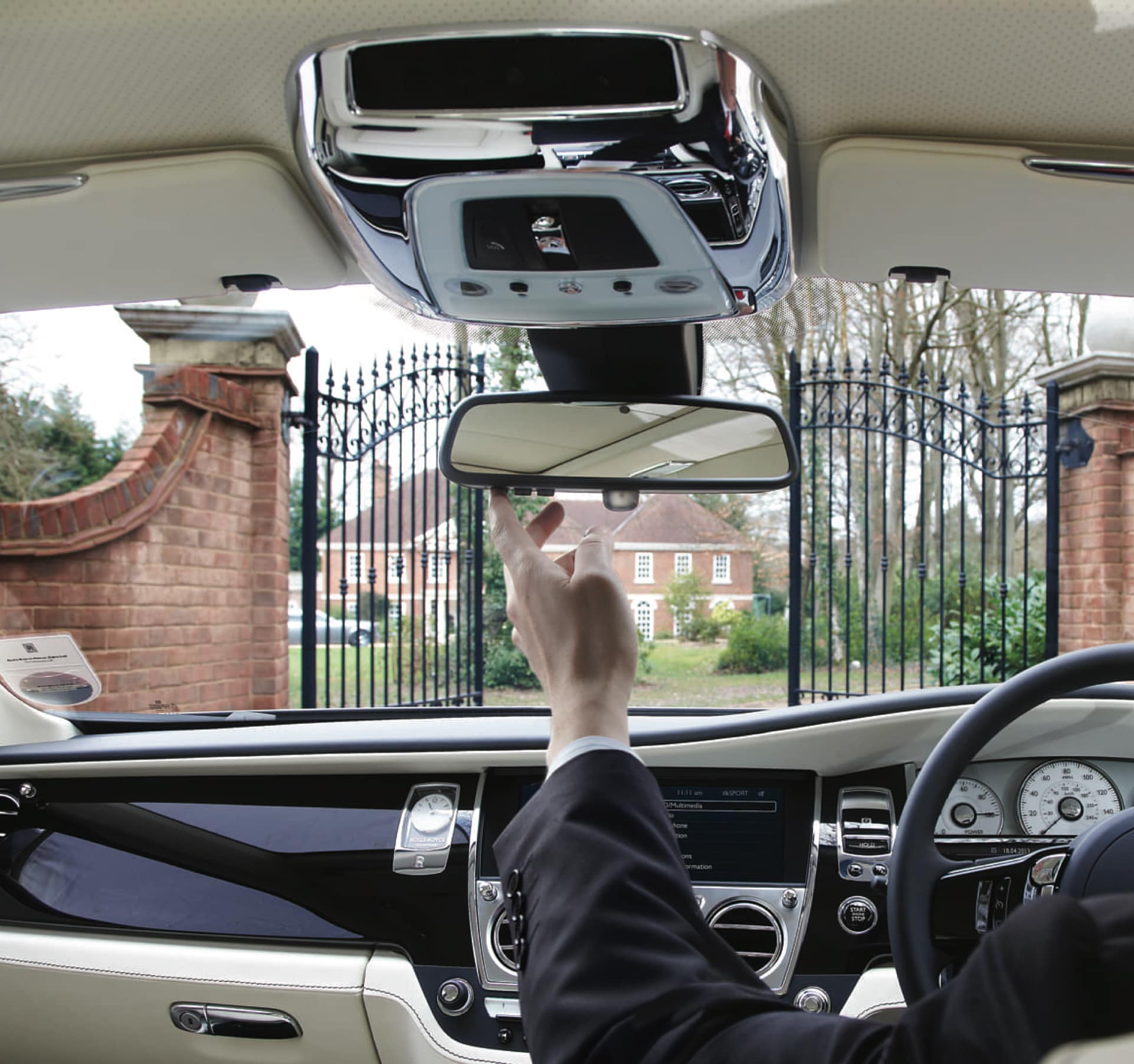 Driver of Rolls-Royce motor car operating Universal Remote Control with control buttons fitted to the replacement rear view mirror