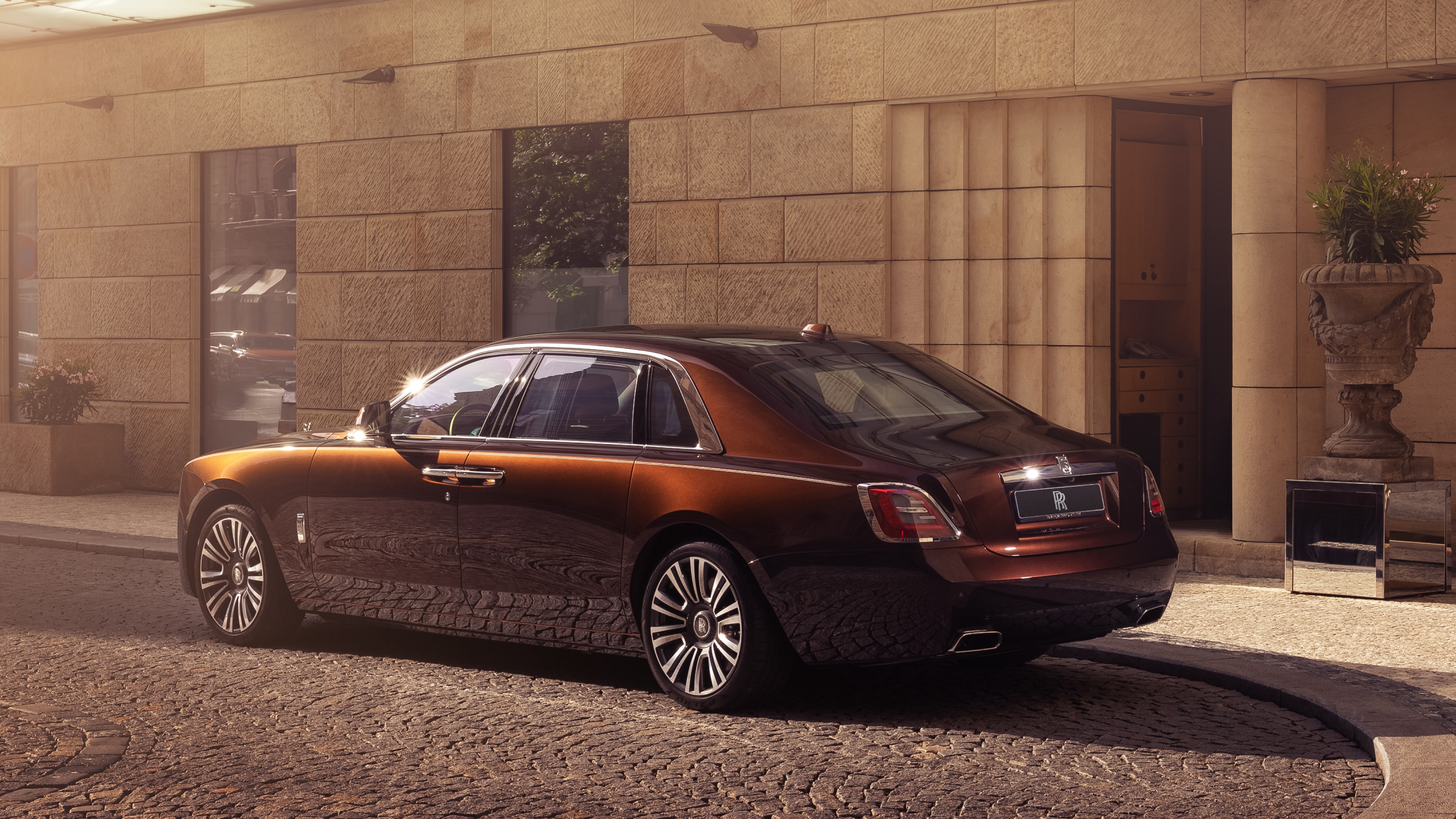 A Rolls-Royce car in the shadow next to a building