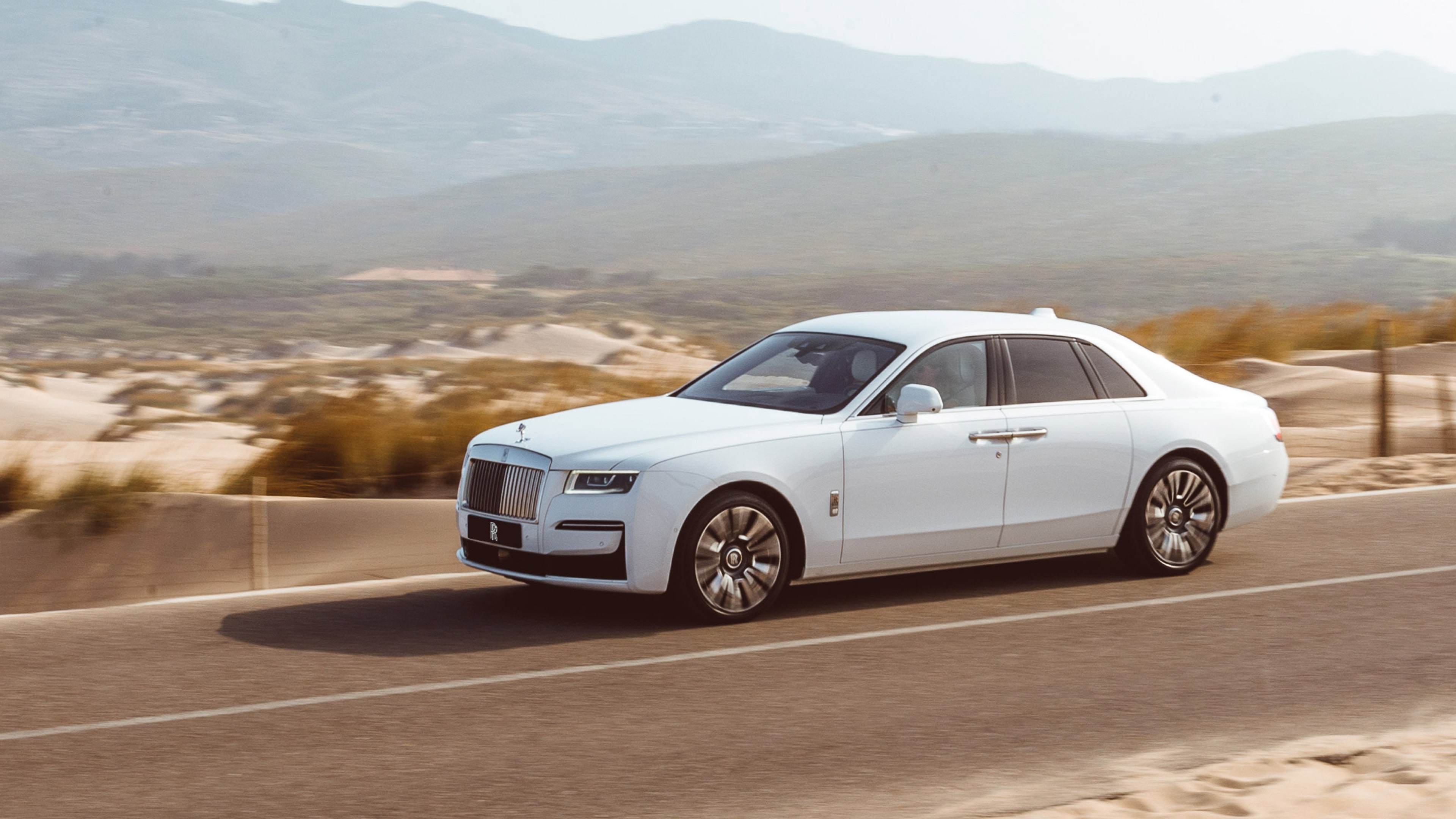 A white Rolls-Royce car in the road