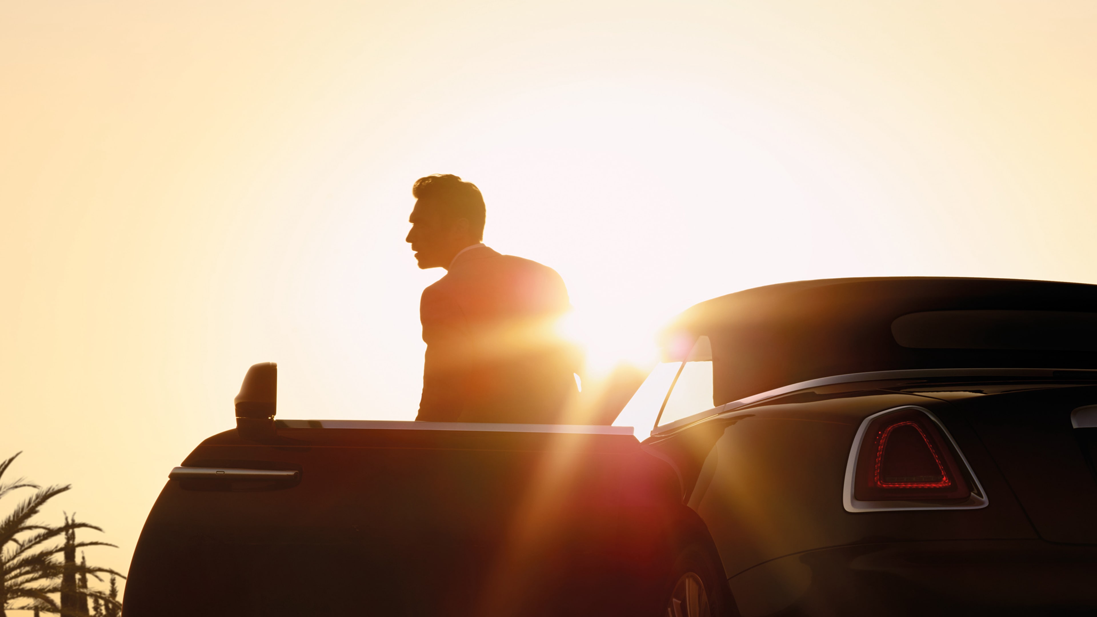 A man leaving his Rolls-Royce car during sunset