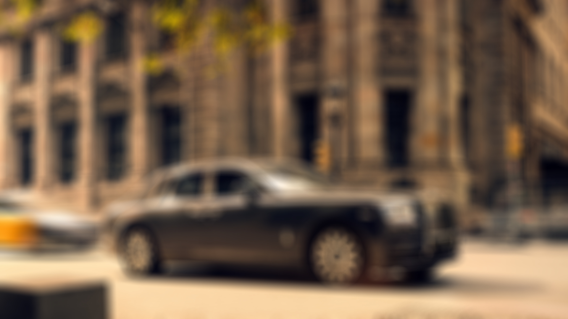 A side profile shot of a black Rolls-Royce Phantom parked on a road