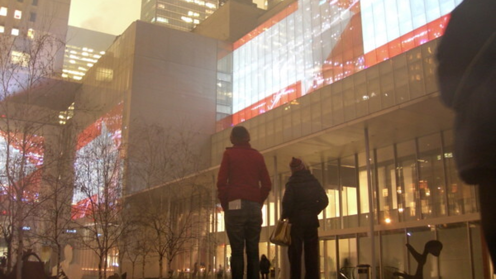 Doug Aitken image. Two people stating up at buildings in the night