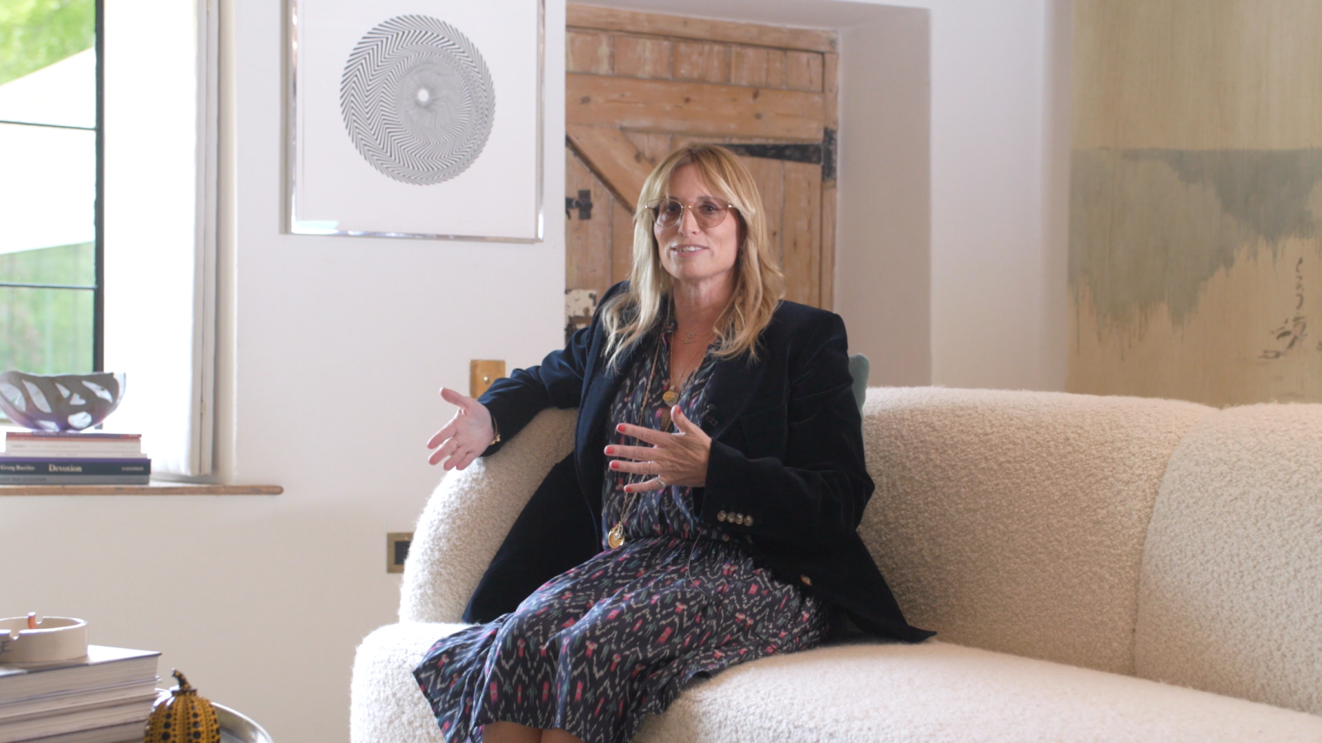 Jane Suitor seated in front of a Bridget Riley print.Jane Suitor at Lypiatt House. Imag